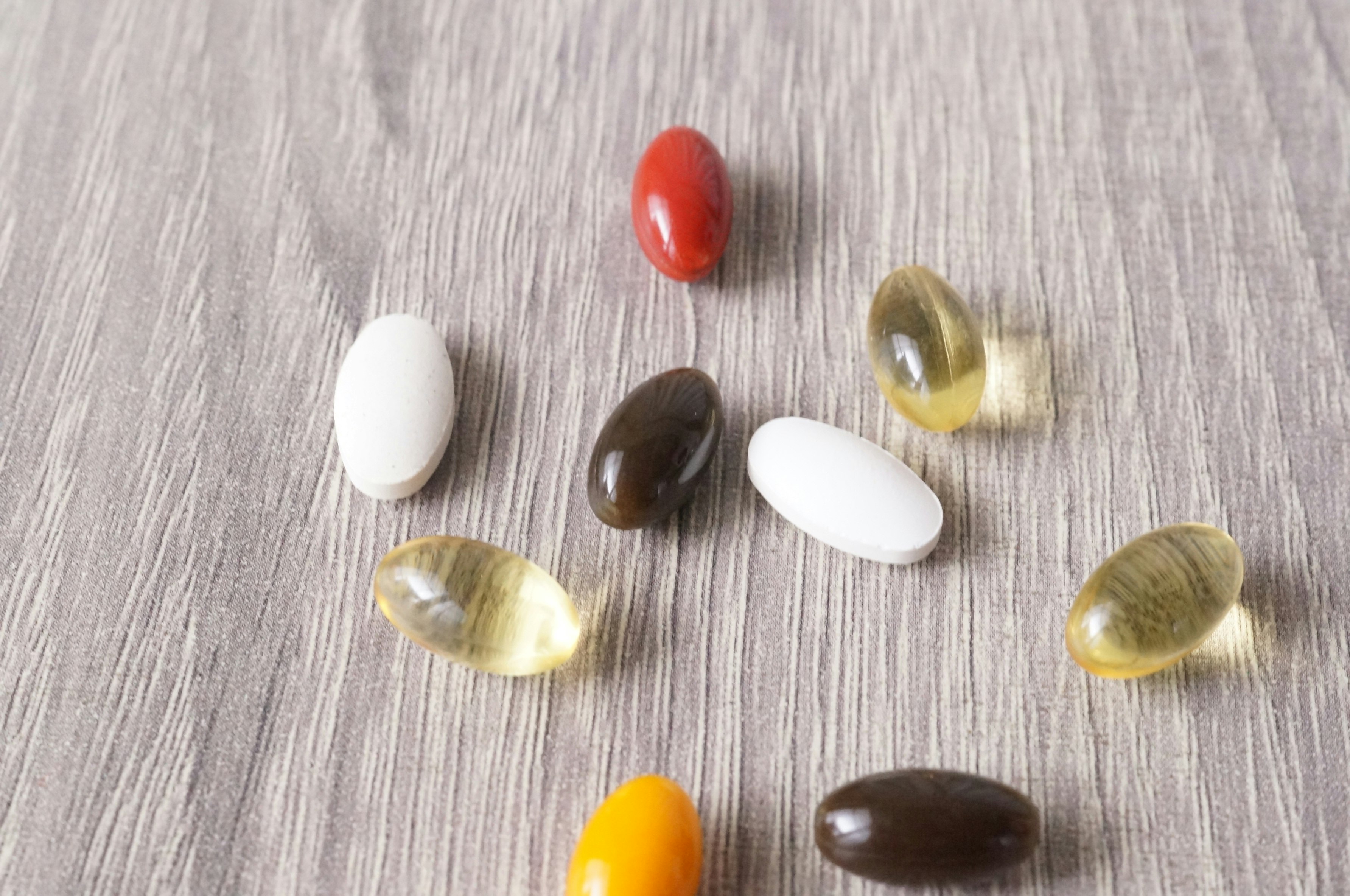 Pastillas de suplementos de colores dispuestas sobre una superficie de madera