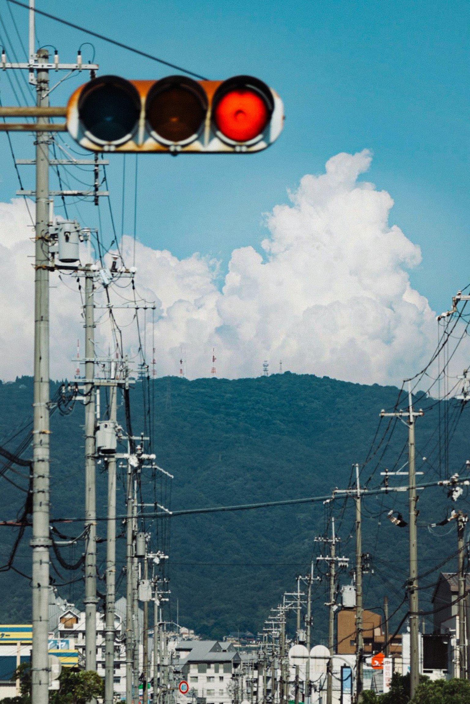 Vista di strada con un semaforo rosso linee elettriche e montagne sullo sfondo