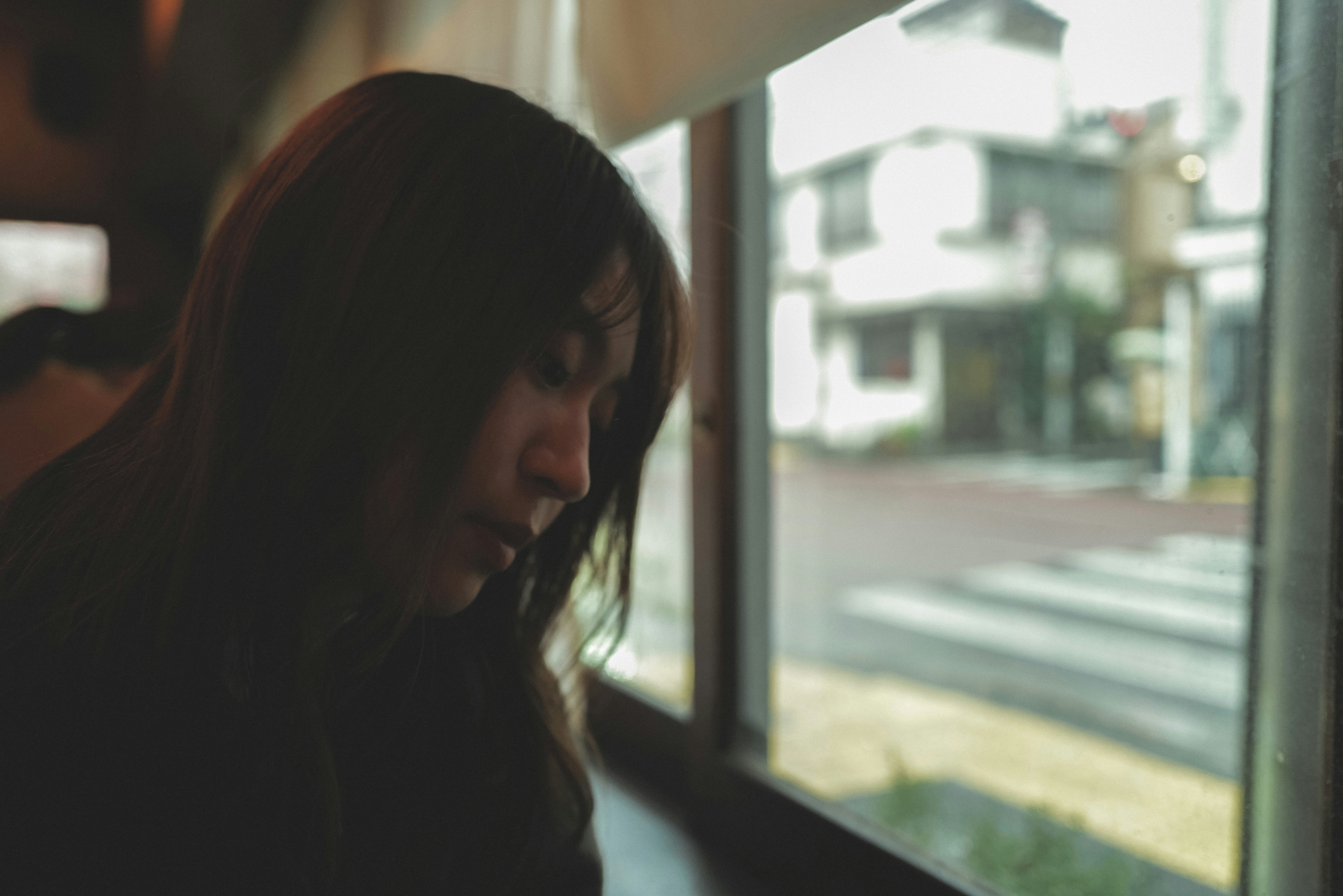 窓辺で頬杖をつく女性の横顔