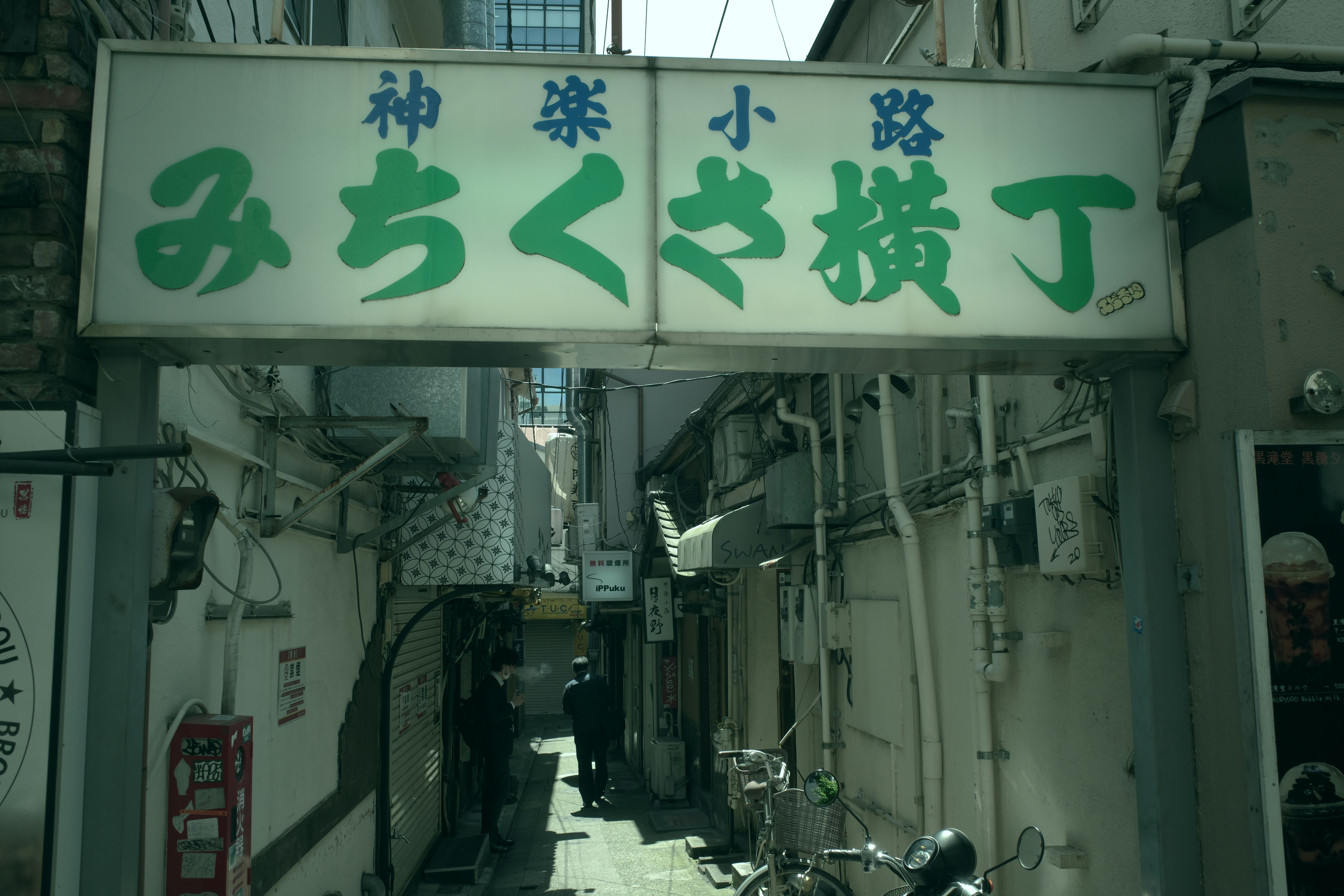 绿牌招示的狭窄商铺巷道里停放的自行车