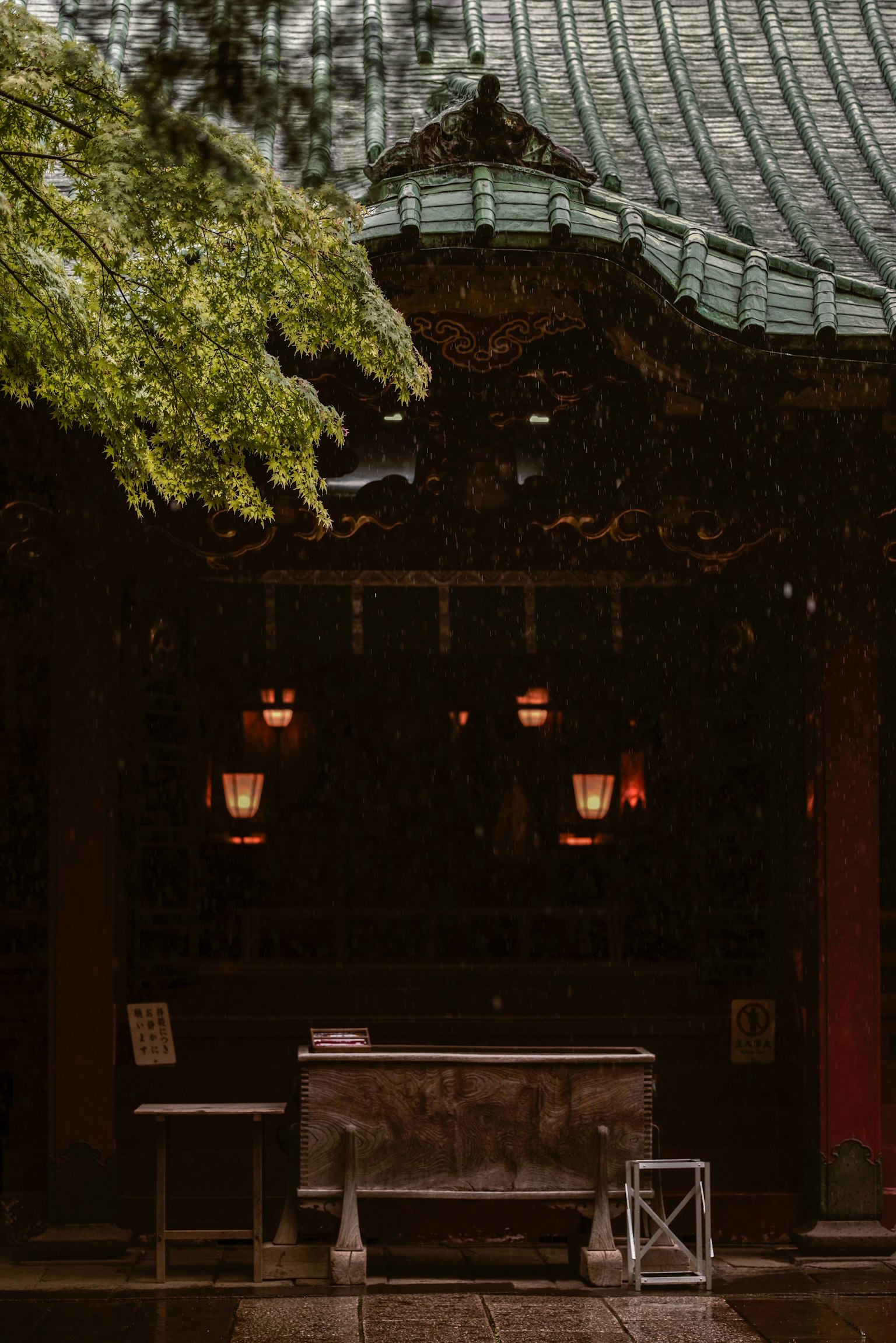 雨中的传统日本神社入口 绿色树木和古老屋顶可见