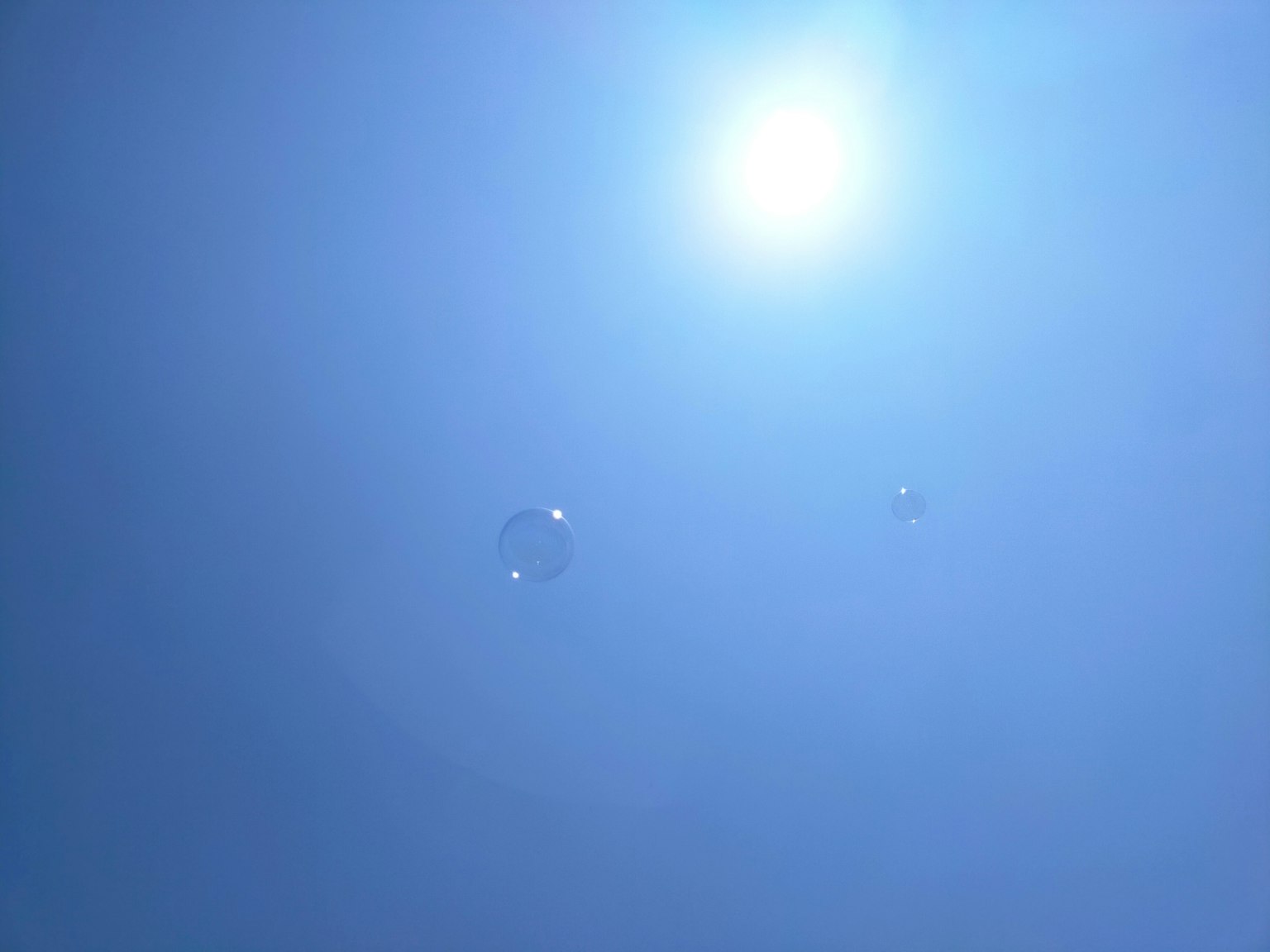Seifenblasen, die in einem blauen Himmel mit der Sonne schweben