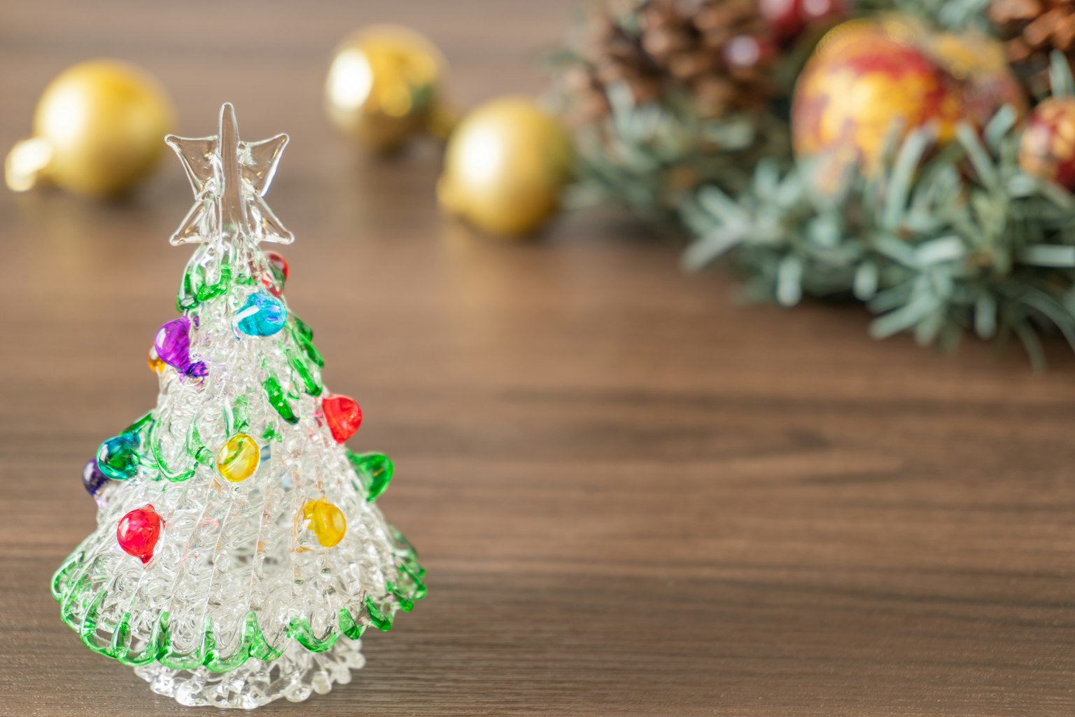 Albero di Natale decorativo in vetro con perline colorate su una superficie di legno