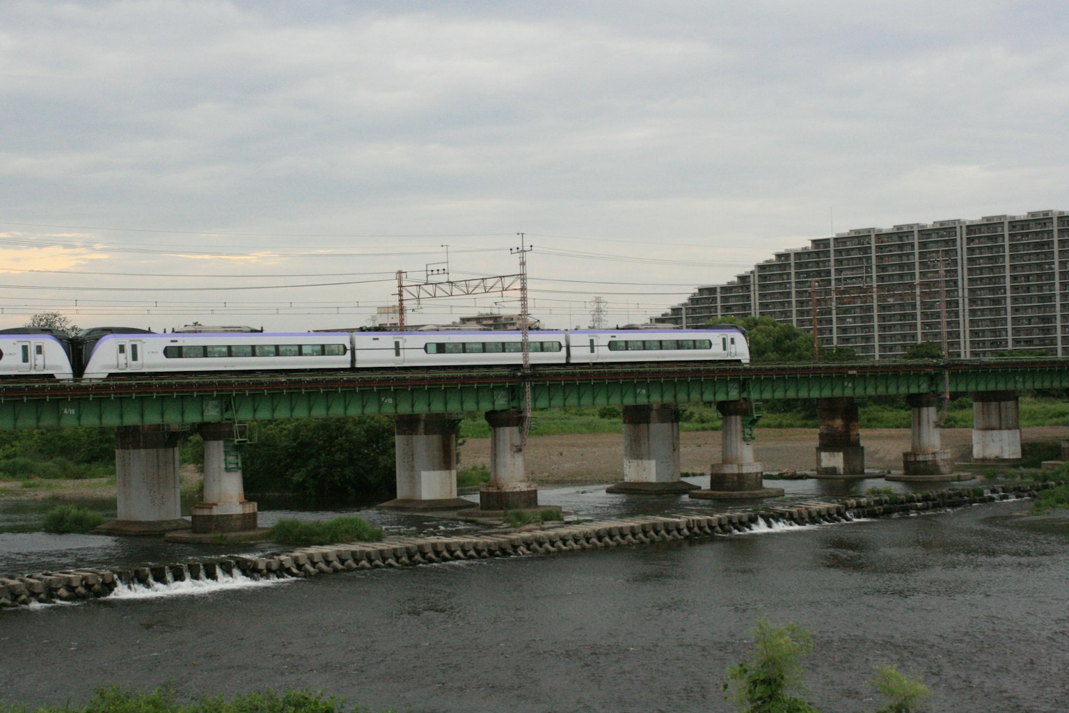 Train crossing a river with surrounding scenery