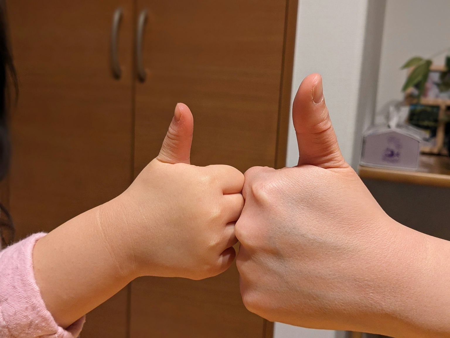 Foto di due pollici alzati che mostrano la mano di un adulto e quella di un bambino