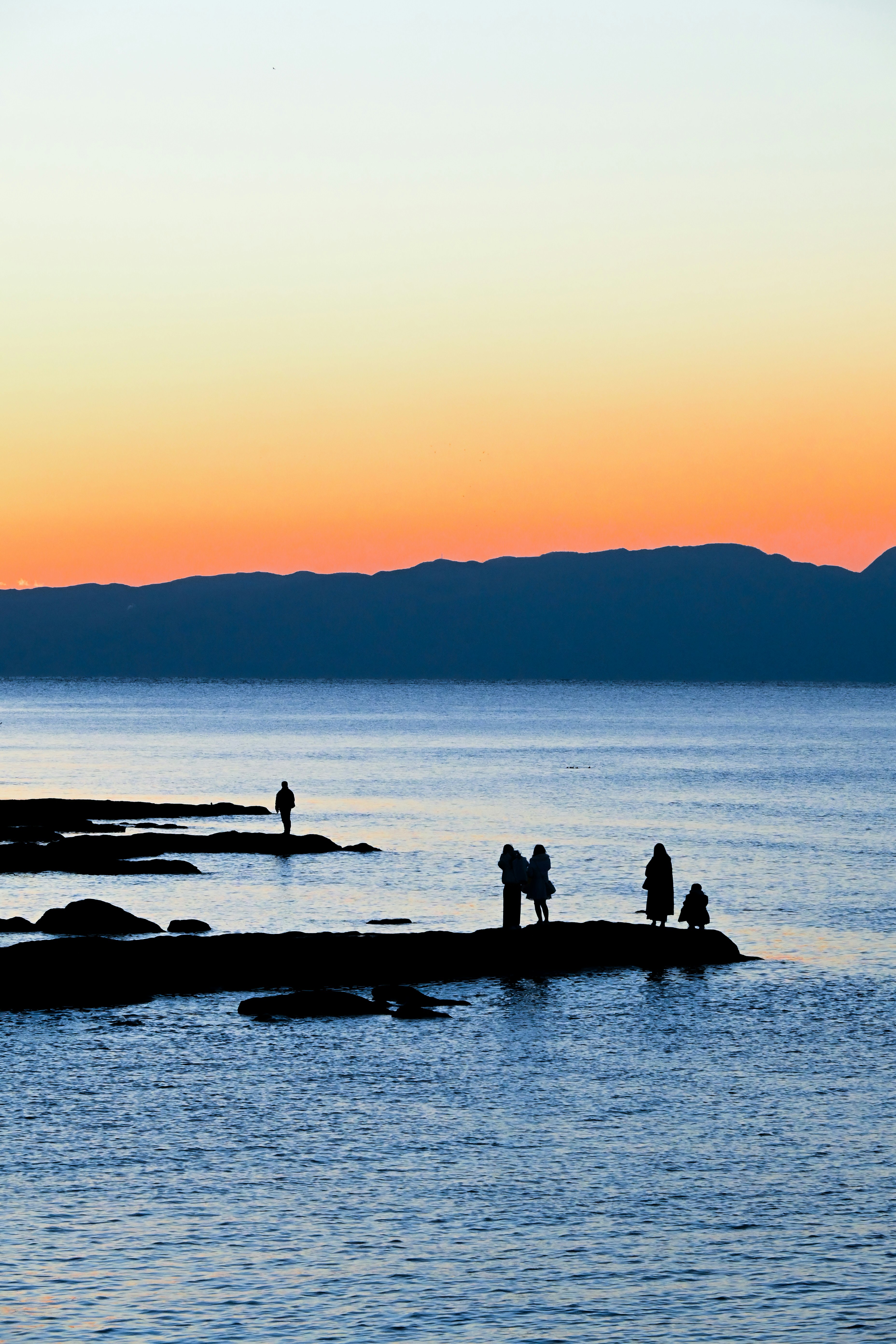 江の島の海岸で夕日を見つめる人々のシルエット