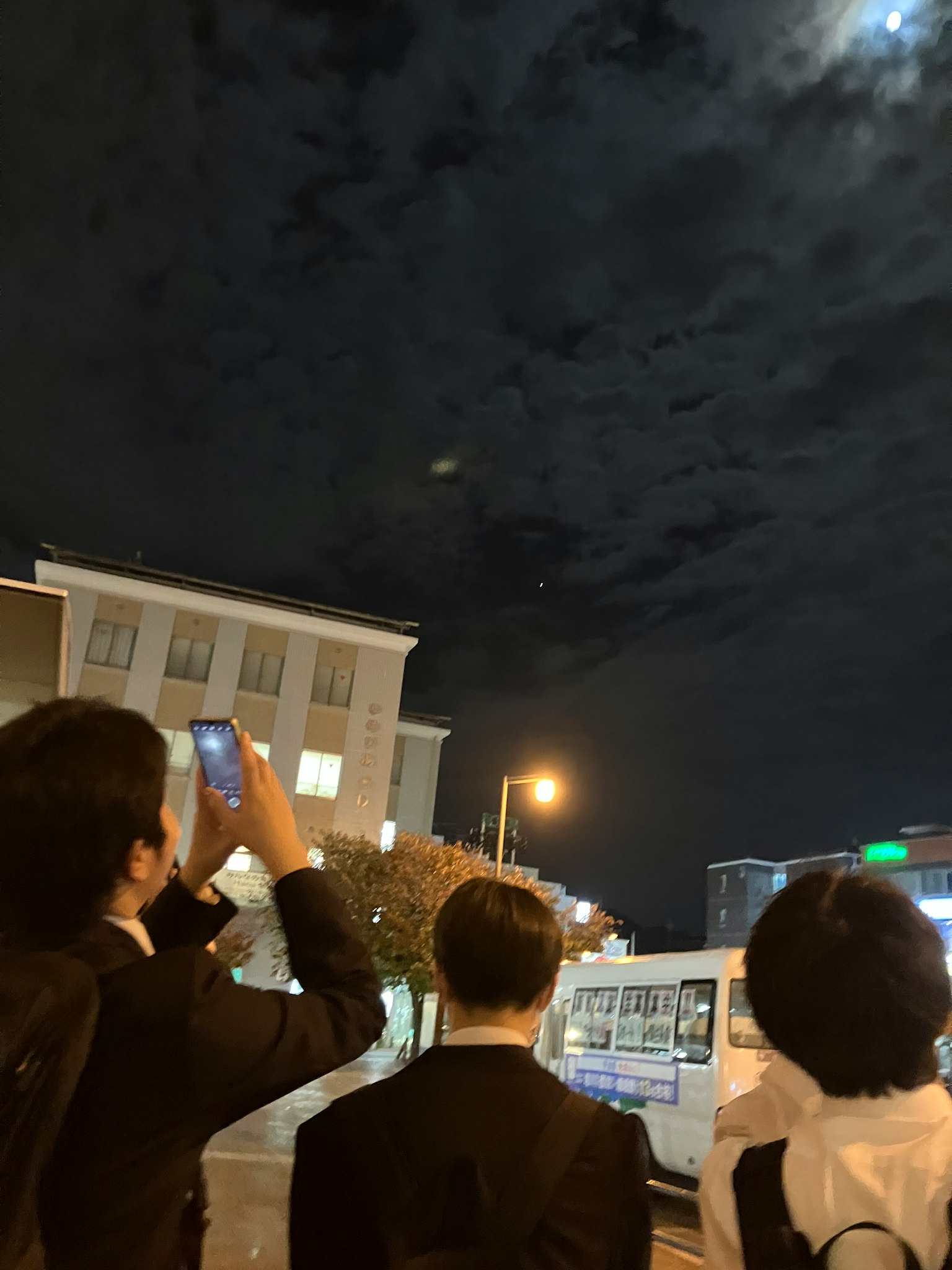身穿西裝的男人們仰望夜空，明亮的月亮照耀著