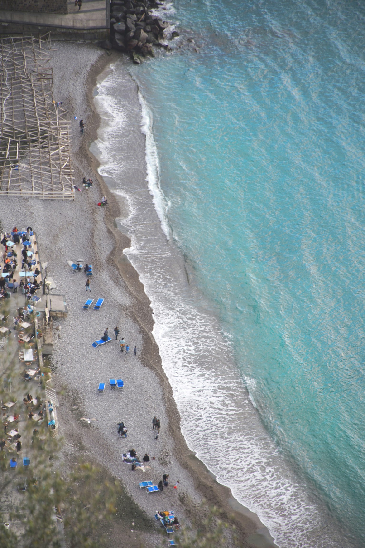 Vista aerea di una spiaggia con acqua blu e riva sabbiosa persone che si godono la spiaggia