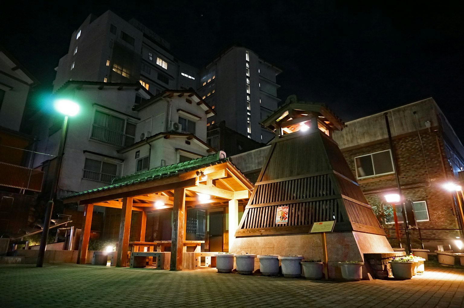 Traditional onsen building illuminated at night surrounded by modern buildings