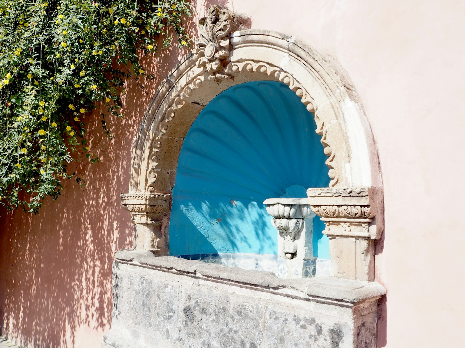 Fontana in pietra ad arco con intagli e sfondo blu