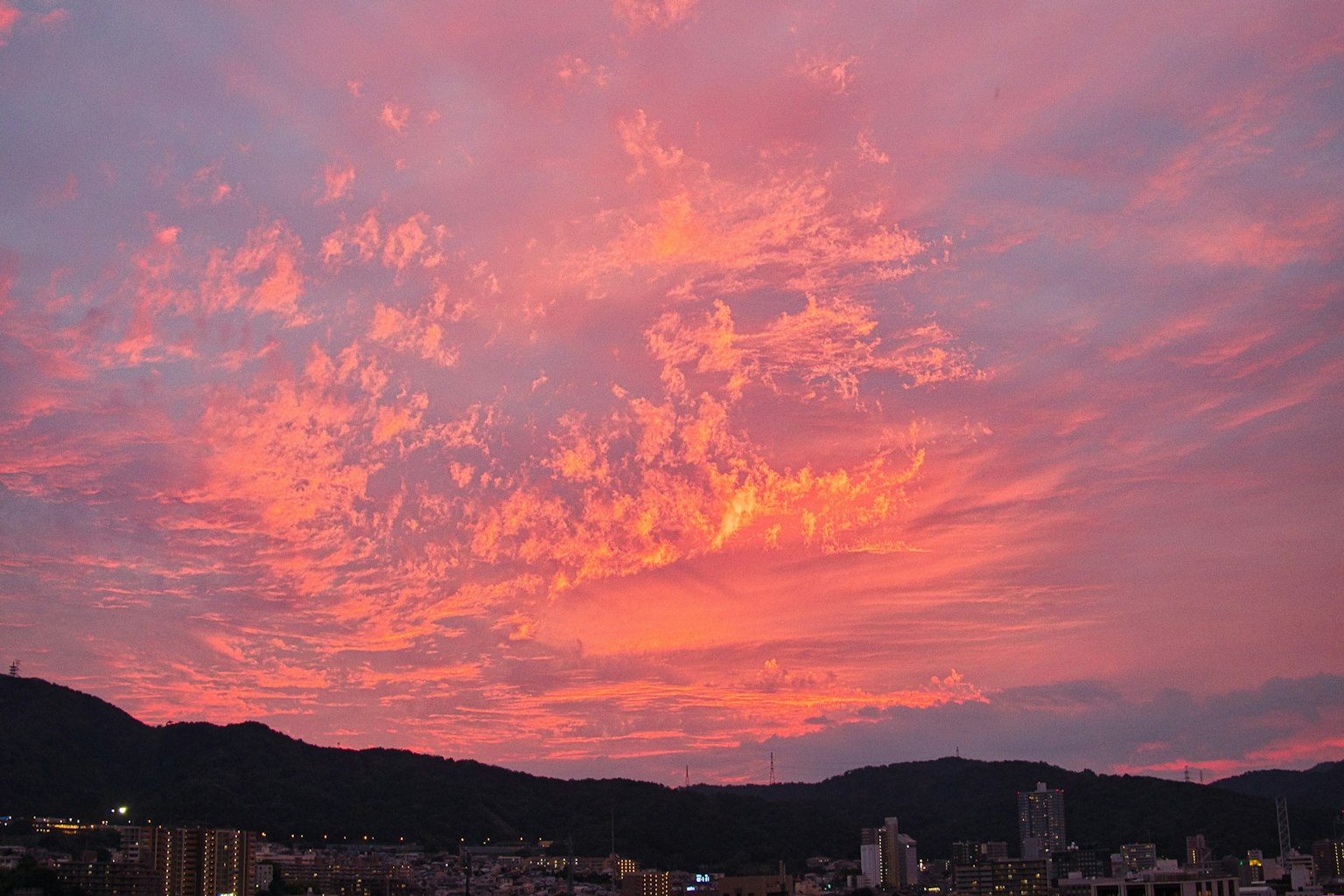 Cielo de atardecer vibrante con nubes coloridas y siluetas de montañas