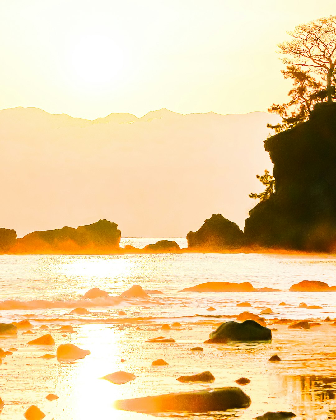 富山湾の気嵐と夕日の海岸風景