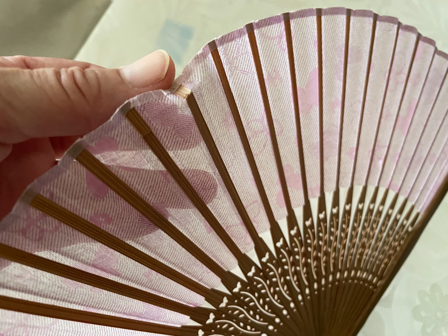 Una vista detallada de un hermoso abanico rosa sostenido con la mano