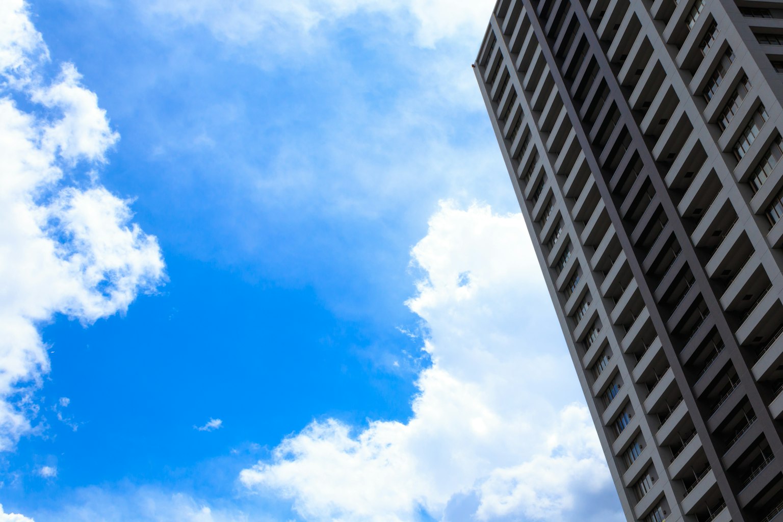 Tall building against a bright blue sky with clouds