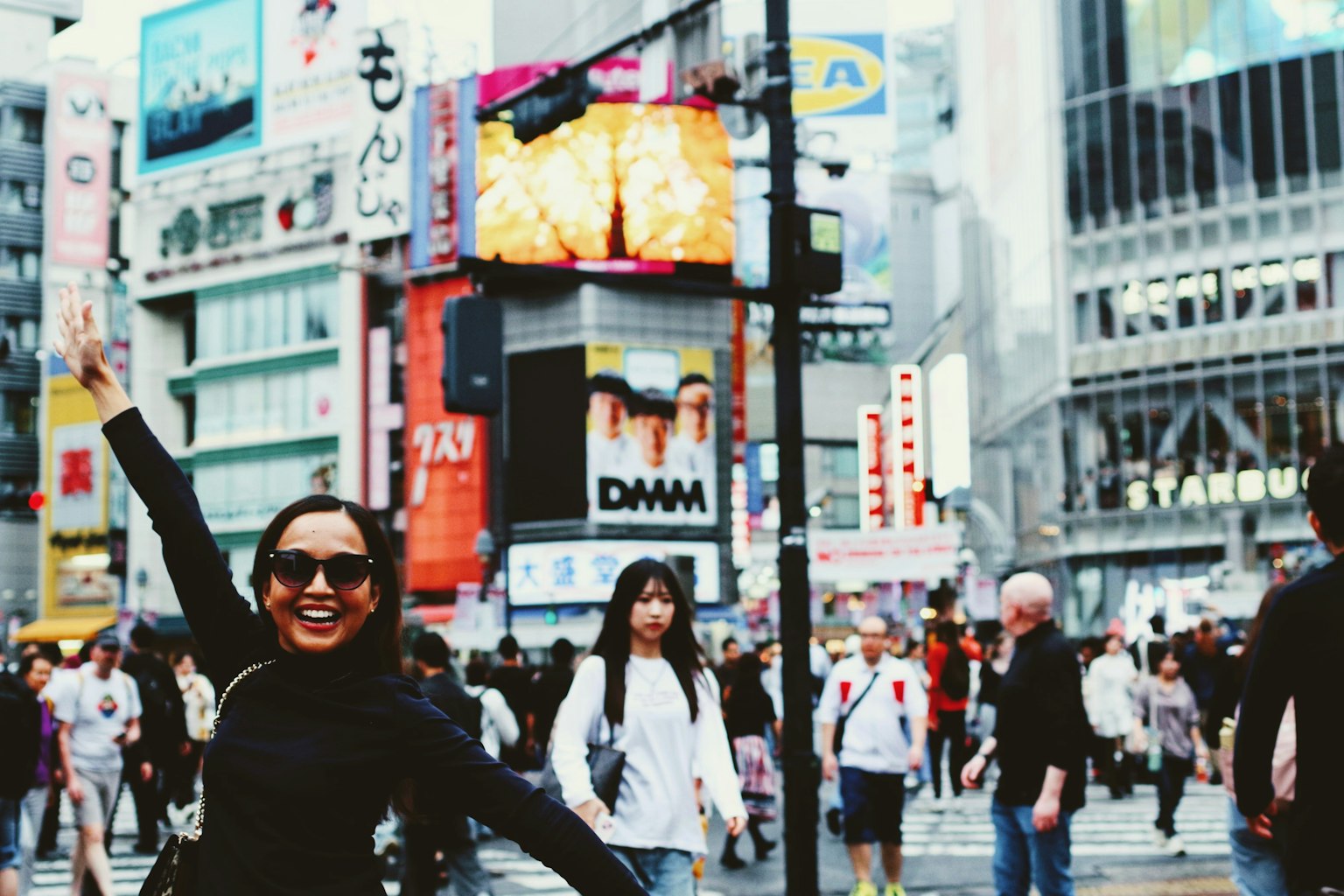 Một người phụ nữ mỉm cười tại Ngã tư Shibuya với bối cảnh thành phố nhộn nhịp