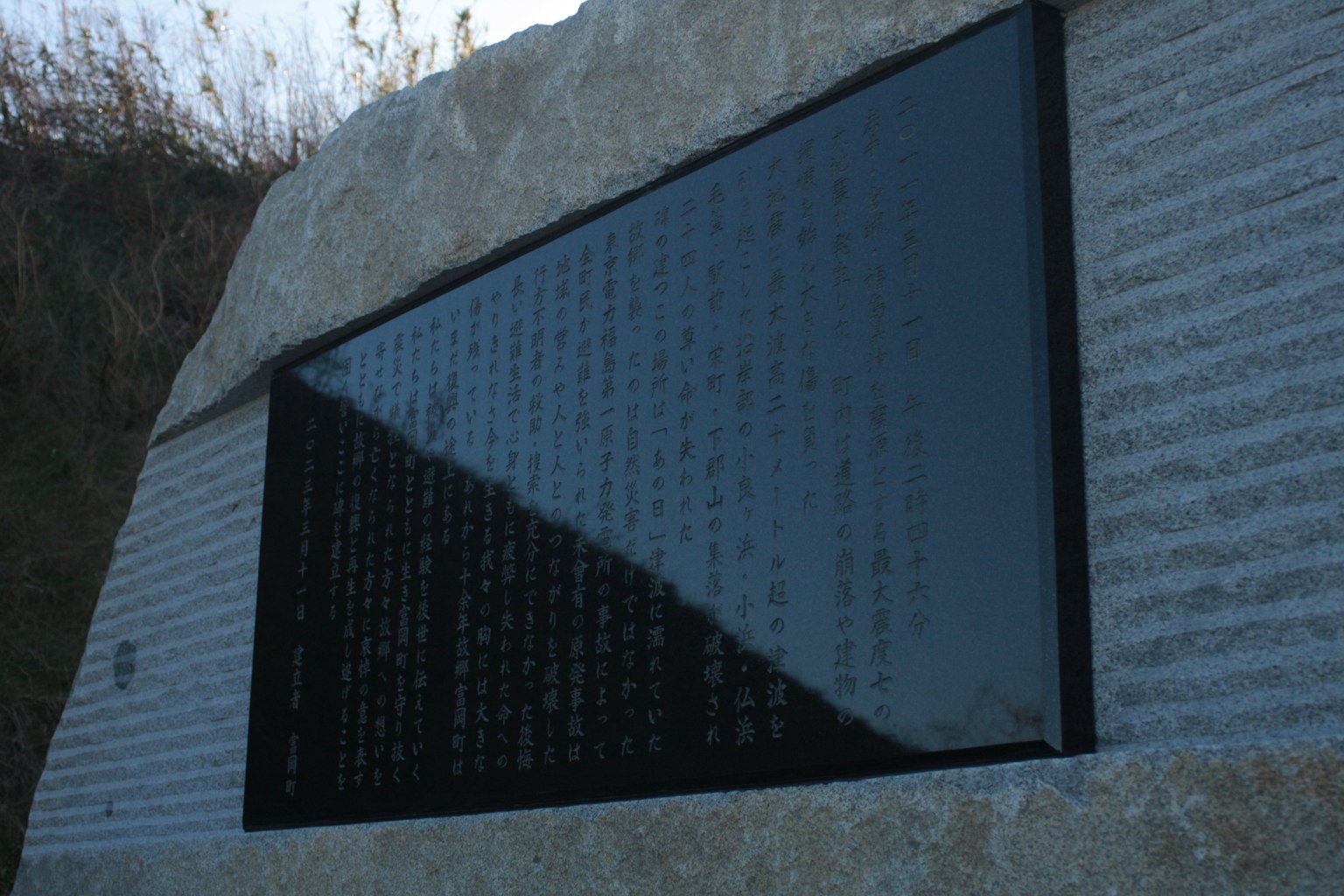 Ein Steindenkmal mit einer schwarzen Tafel mit eingraviertem Text