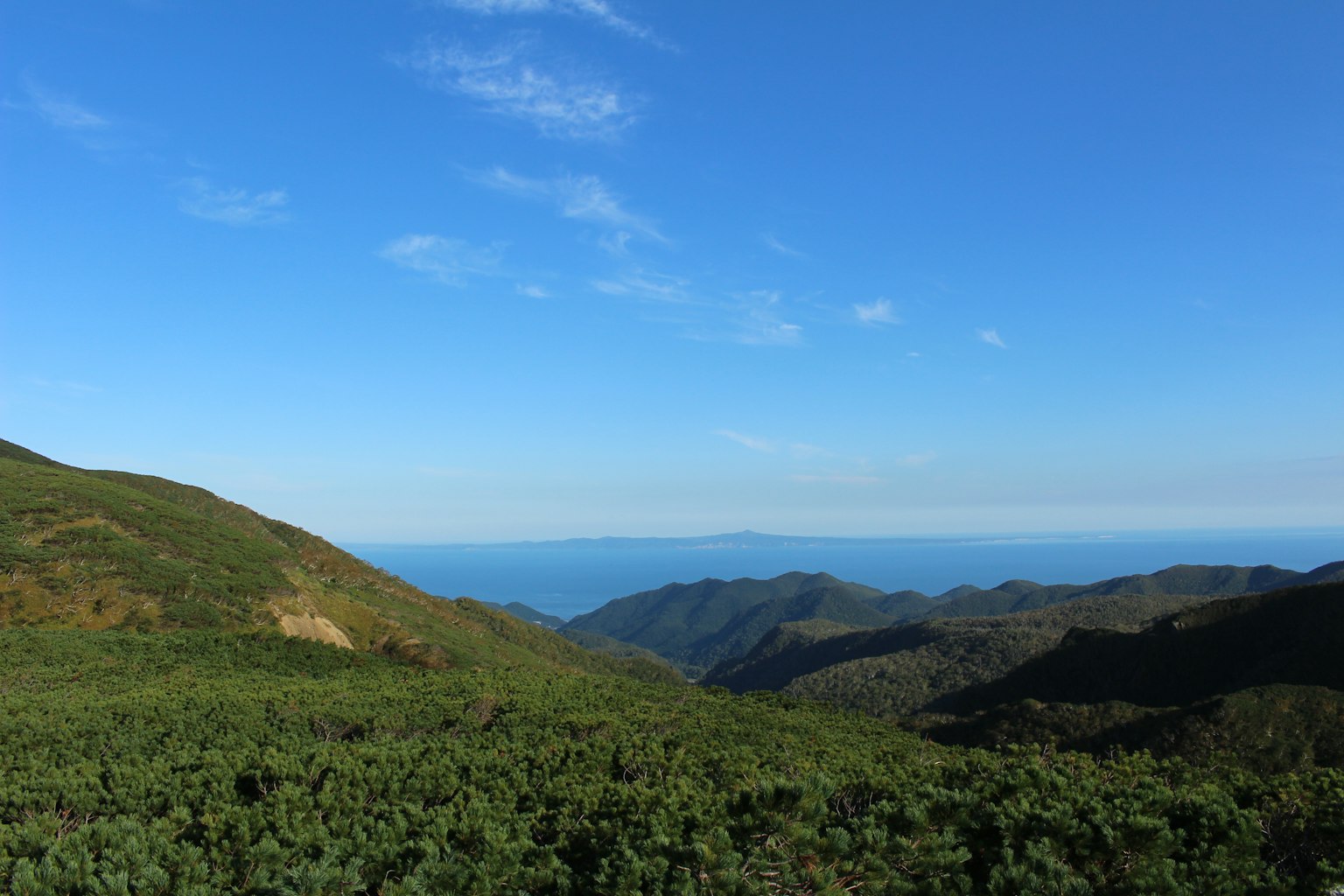 Vista panoramica di colline verdi e oceano blu sotto un cielo sereno
