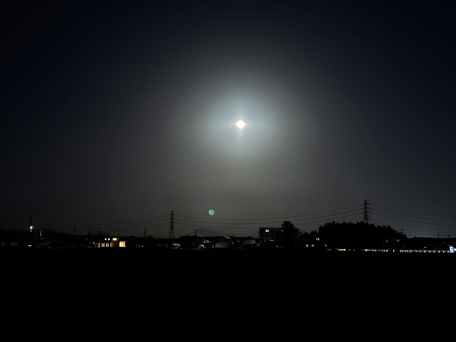 Luna brillante en el cielo nocturno con un paisaje brumoso