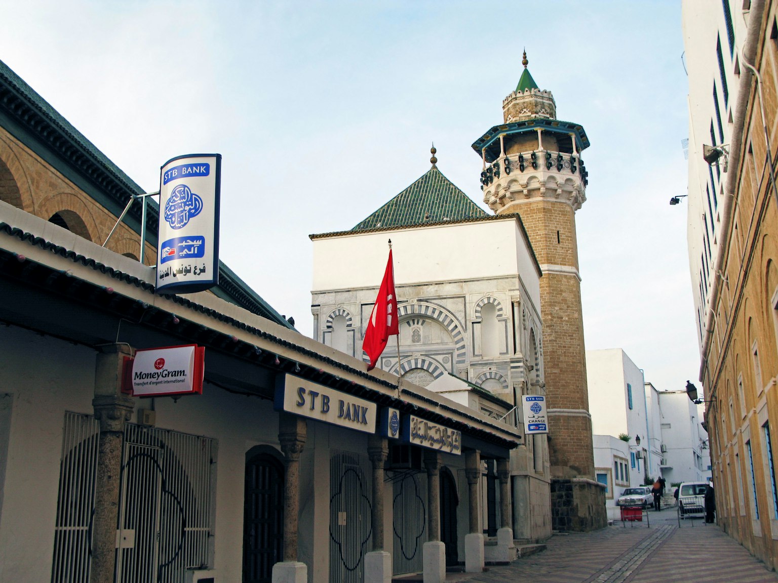 Pemandangan jalan dengan masjid dan menara dengan bendera merah