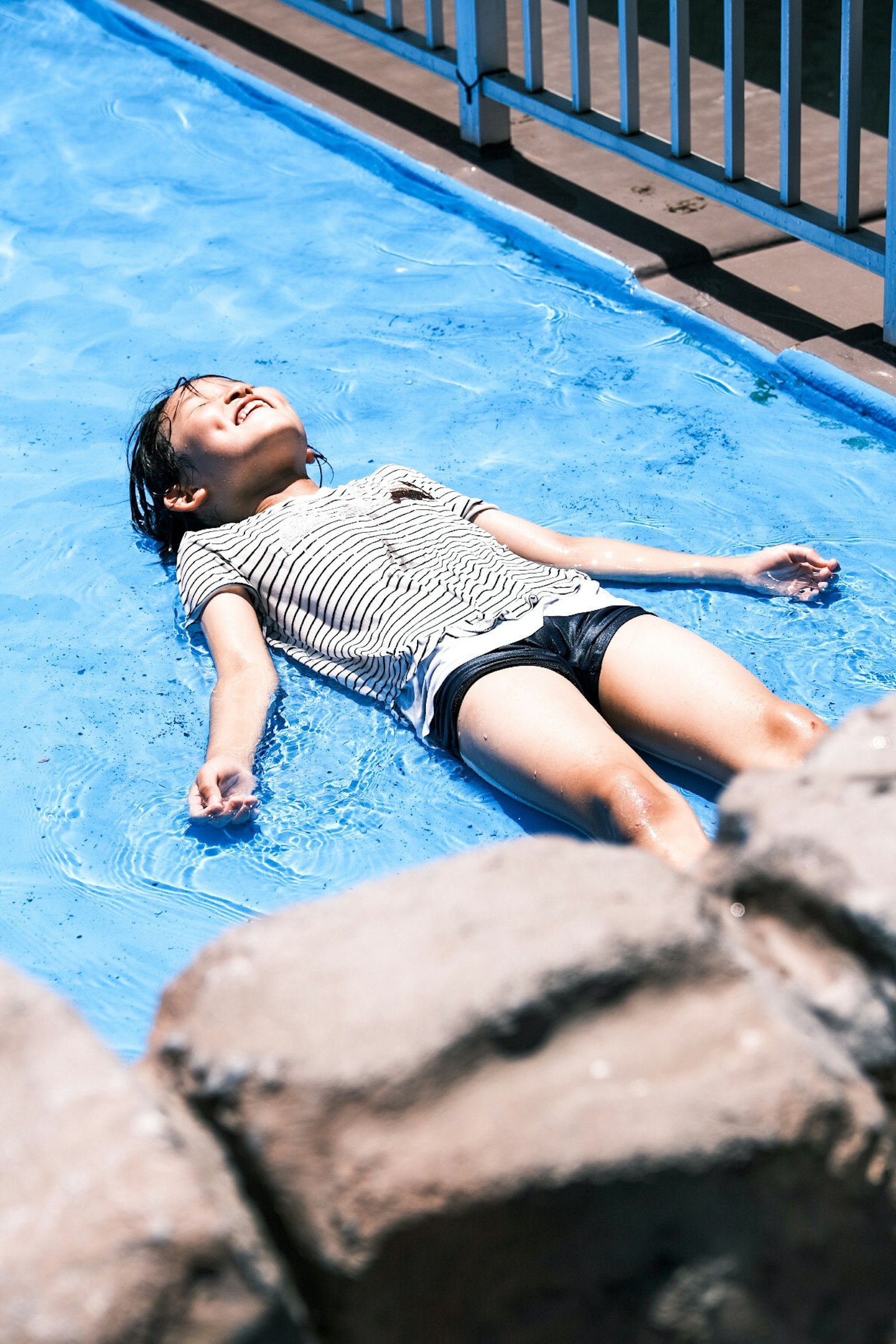 Una ragazza che si rilassa in una piscina blu al sole