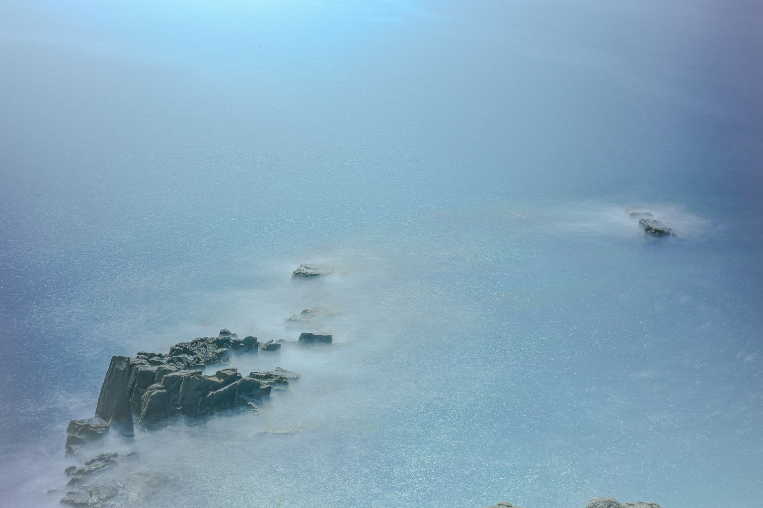 Vista panoramica di una costa rocciosa con nebbia sopra l'oceano blu