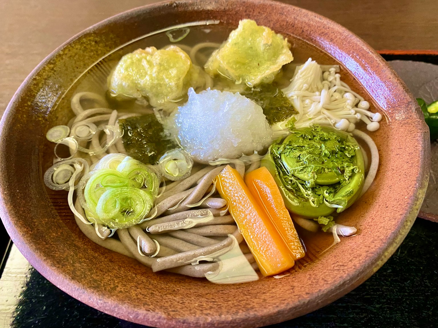Warme Soba-Nudeln serviert mit geriebenem Daikon und verschiedenen Gemüsesorten