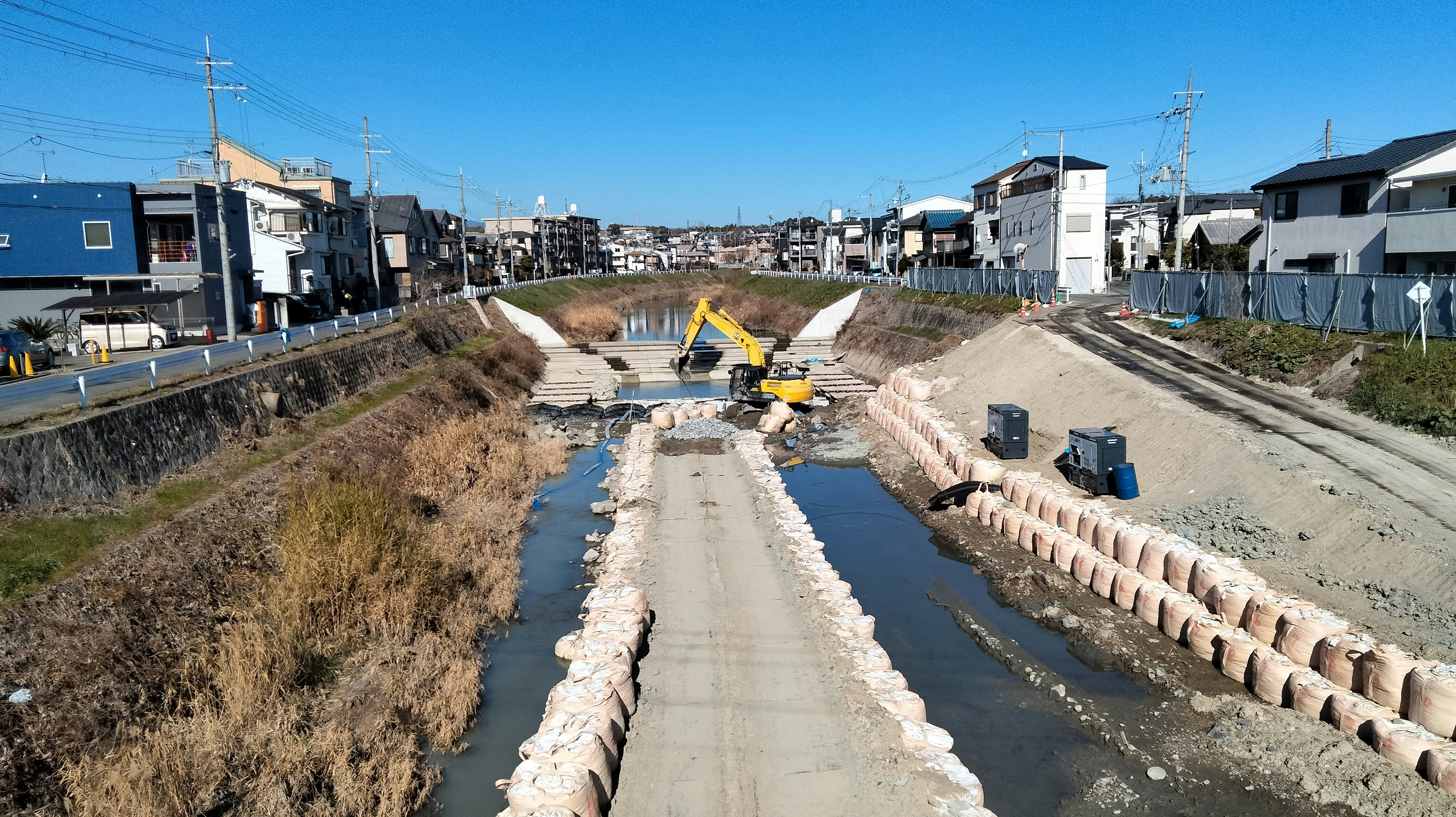 civil engineering work site with concrete-lined drainage channel and excavator