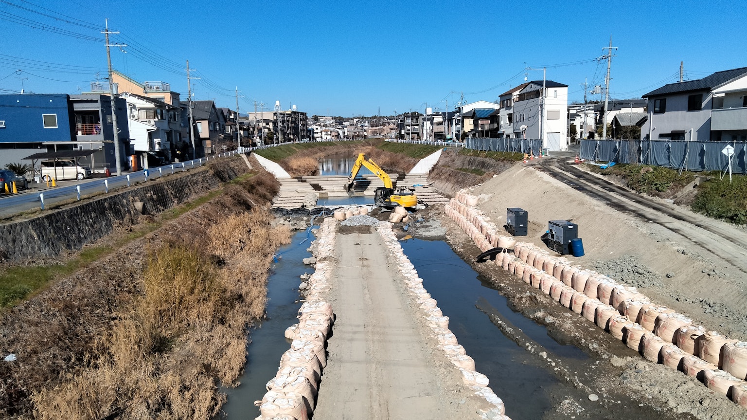 Cantiere lungo un fiume con case circostanti visibili