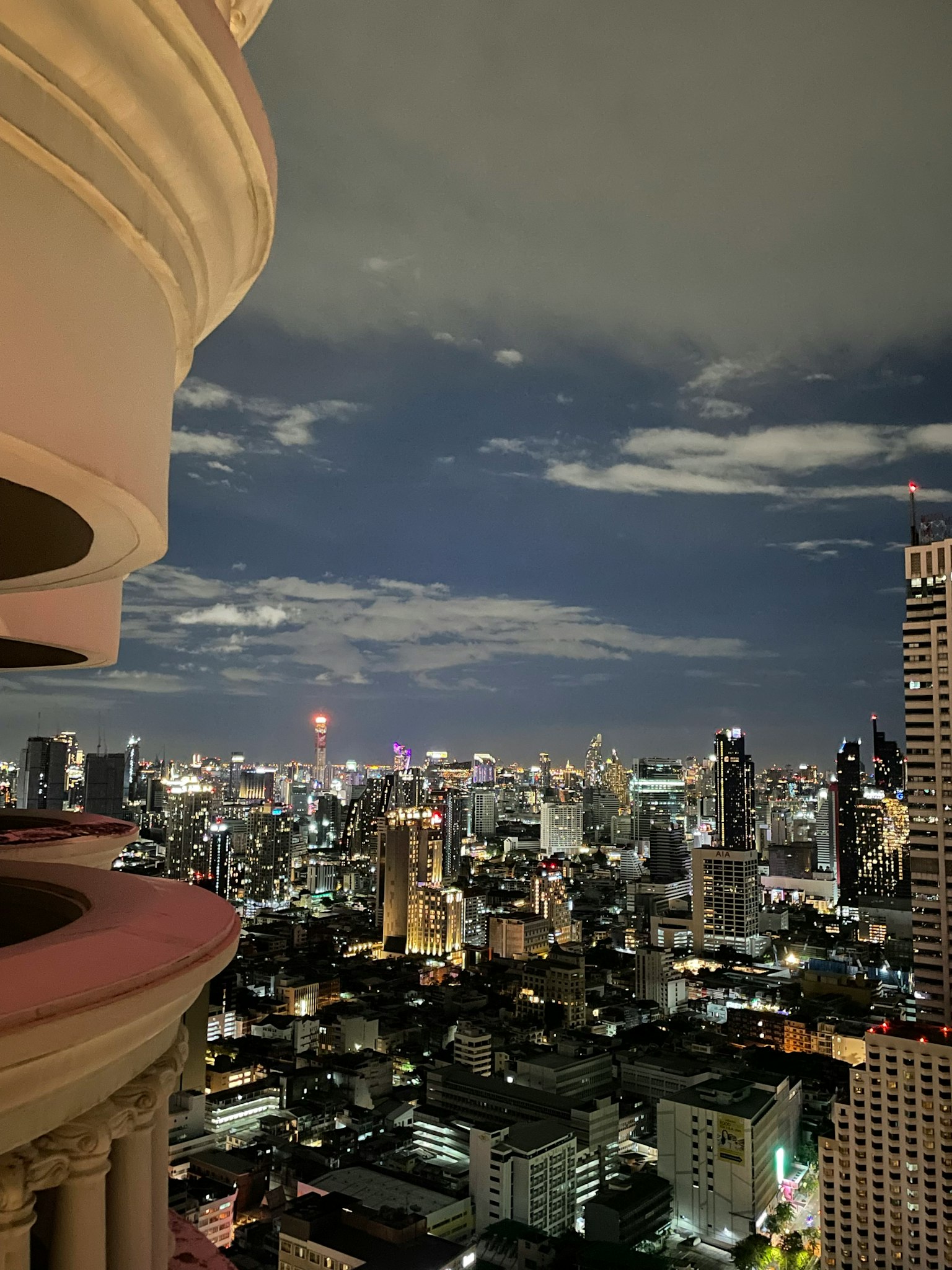 Vue depuis un balcon sur une ligne d'horizon urbaine la nuit bâtiments illuminés et nuages dans le ciel