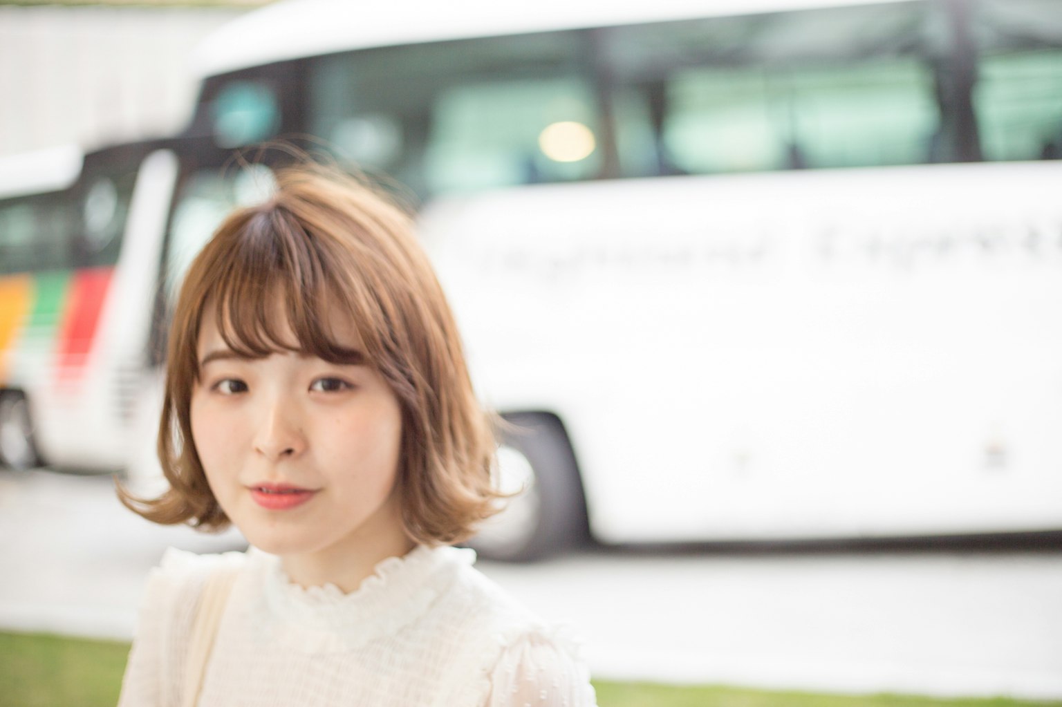 穿白色上衣的年轻女性肖像 背景有一辆公交车