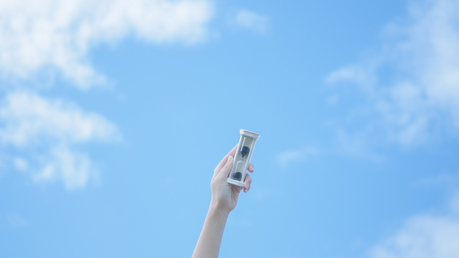 Eine Hand hält ein Gerät vor einem klaren blauen Himmel