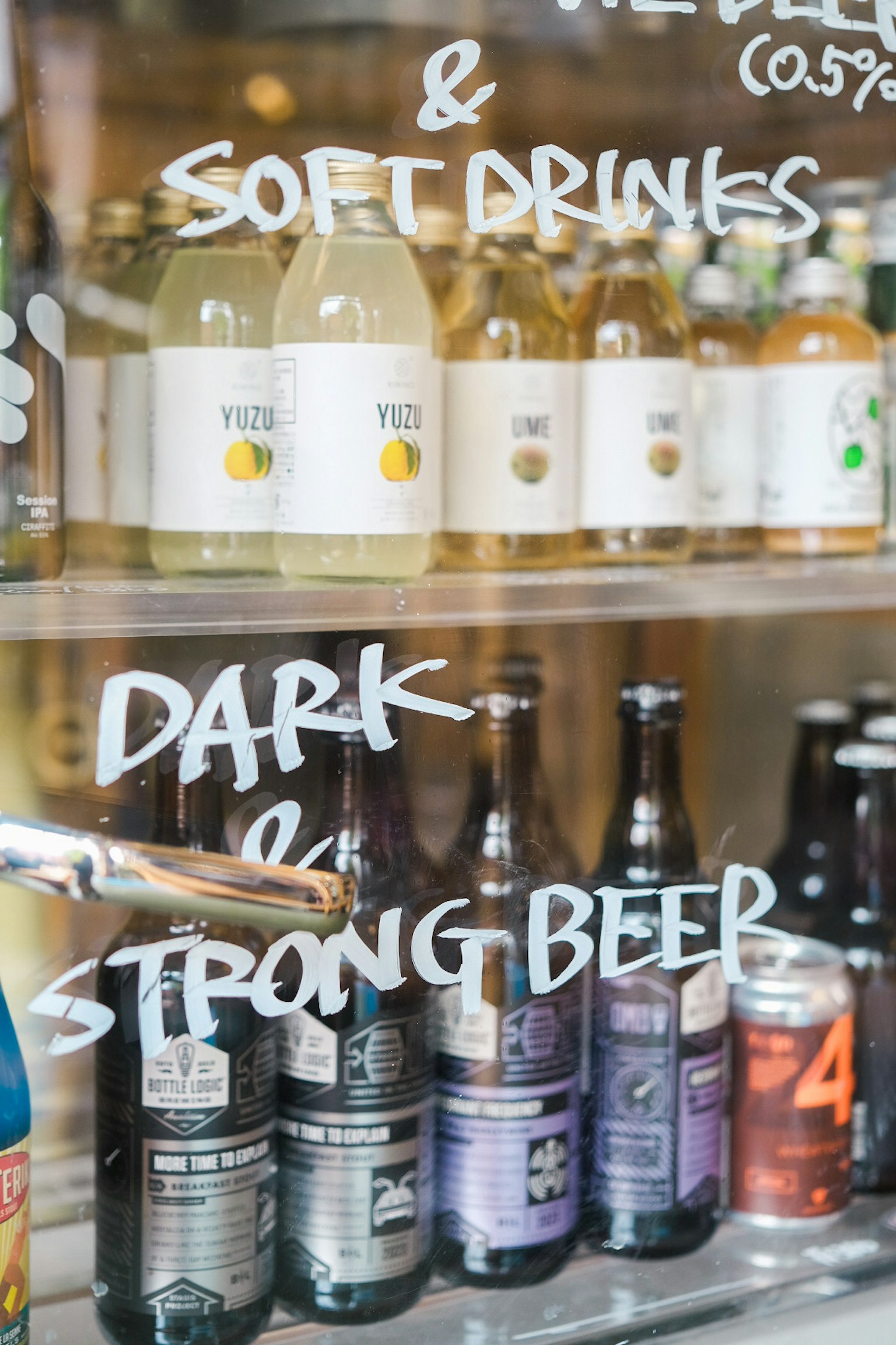 Glasvitrine mit verschiedenen Getränkeflaschen und Etiketten für dunkles und starkes Bier