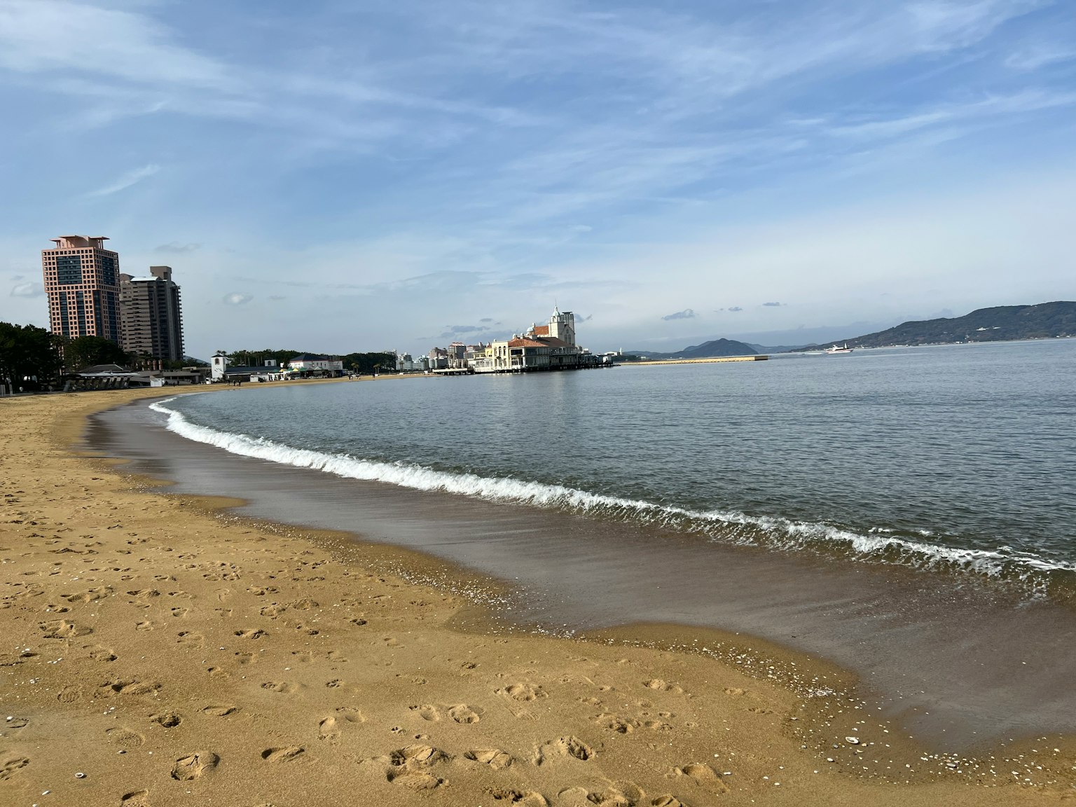 Beach scene with gentle waves and high-rise buildings in the background