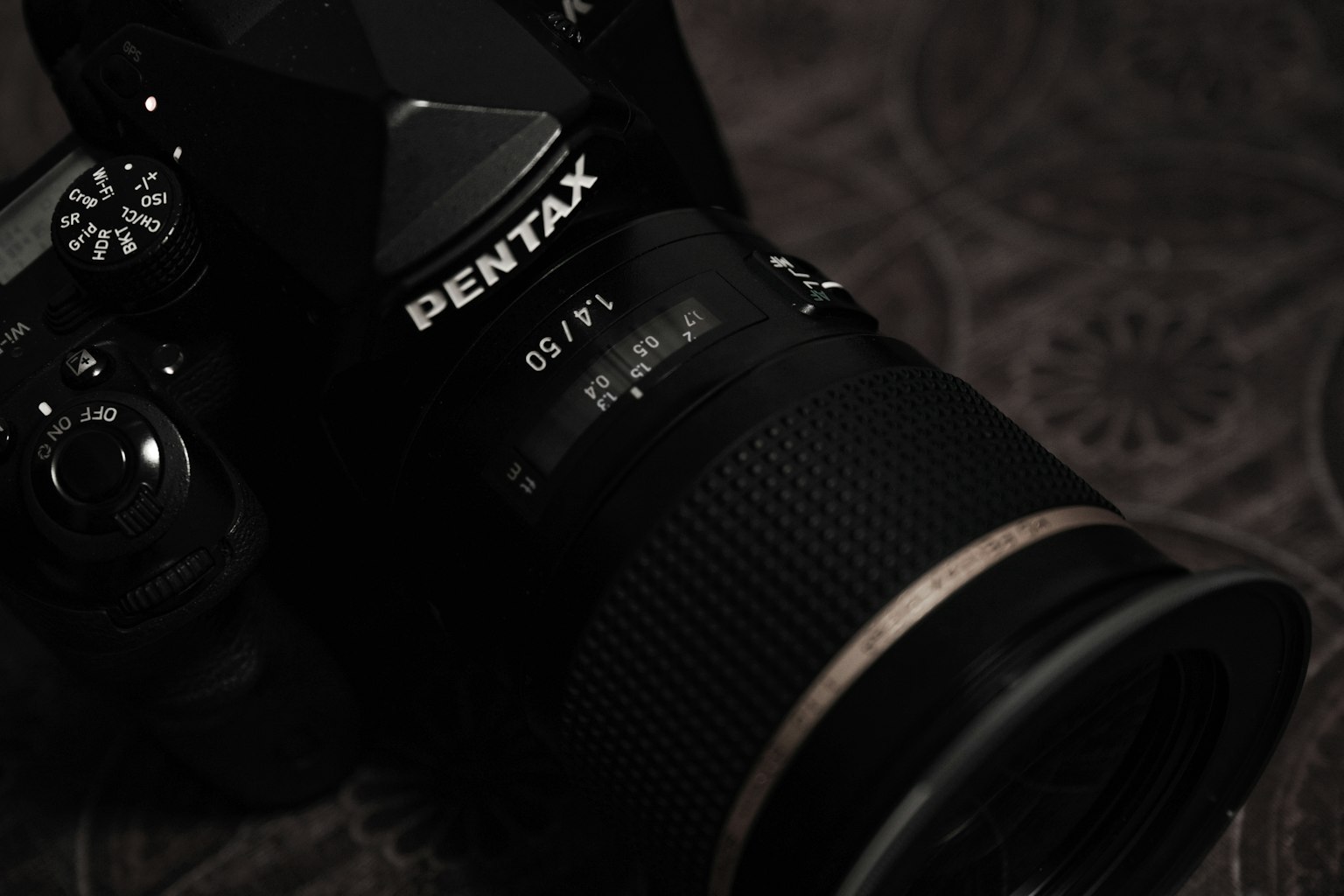 Acercamiento de una cámara Pentax mostrando el objetivo y los detalles