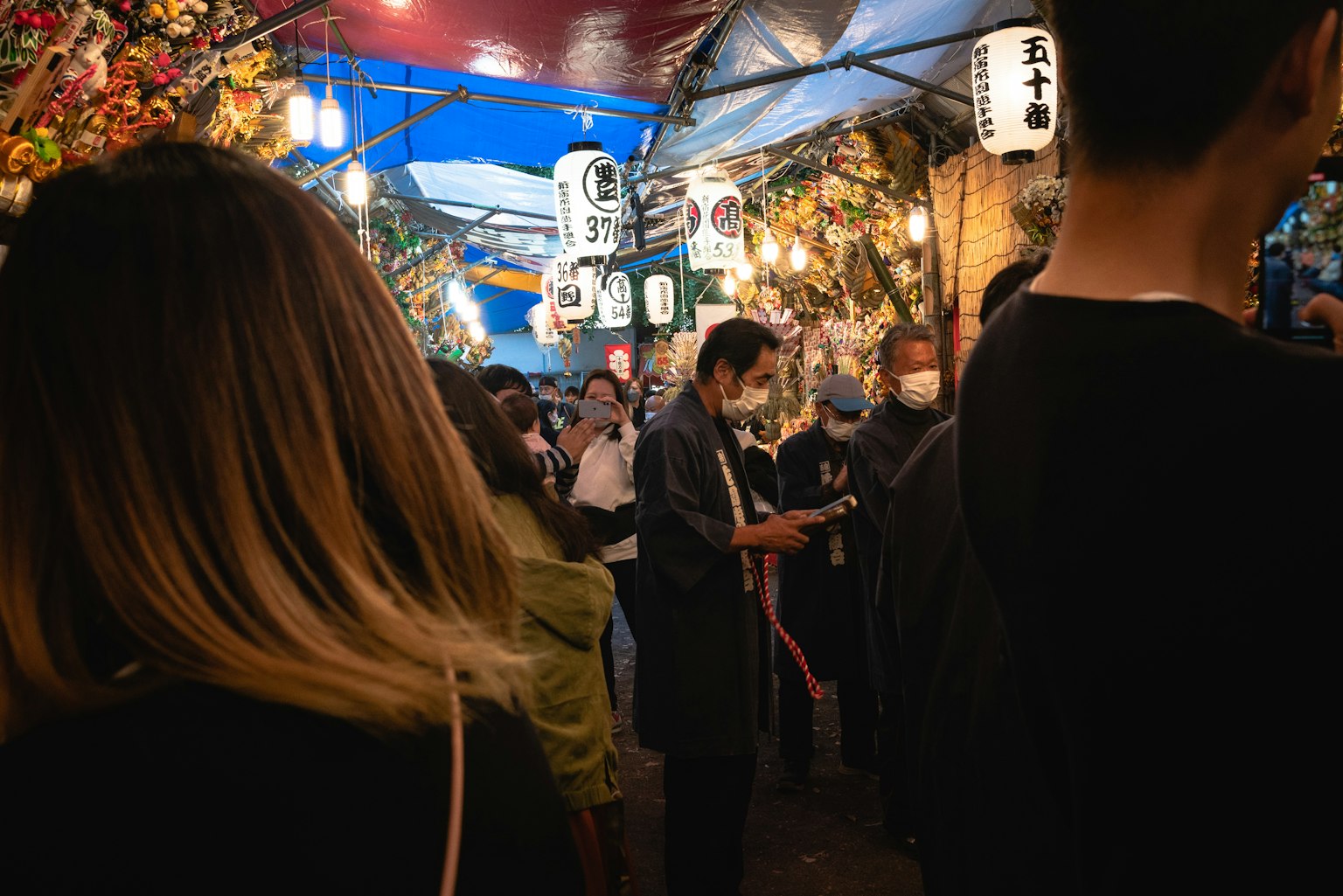 ภาพตลาดกลางคืนที่คึกคักมีแผงขายอาหารผู้คนสนุกสนานในบรรยากาศที่มีโคมไฟส่องสว่าง
