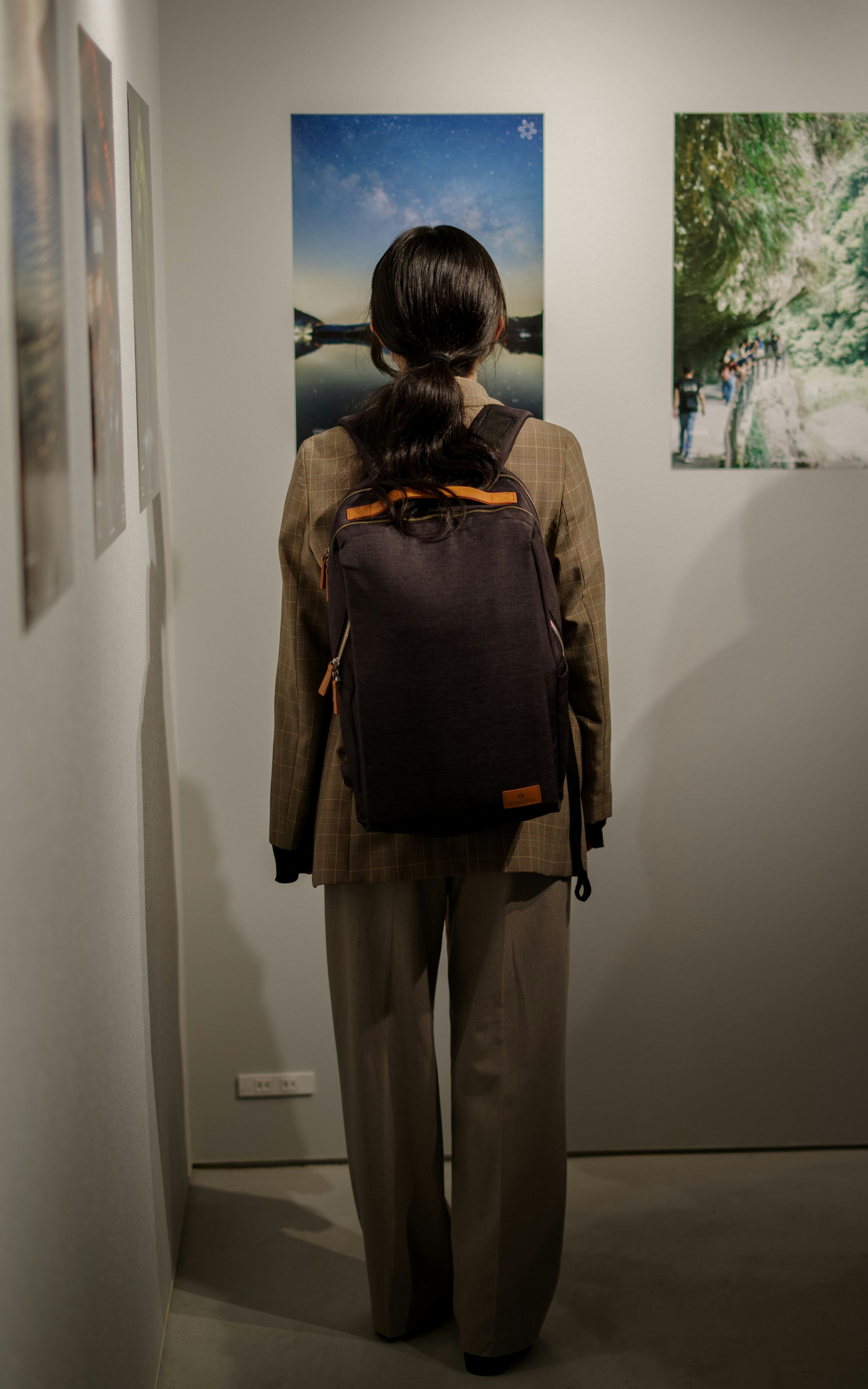 新宿のベースメントギャラリーで壁に並ぶ展示を見つめる後ろ姿