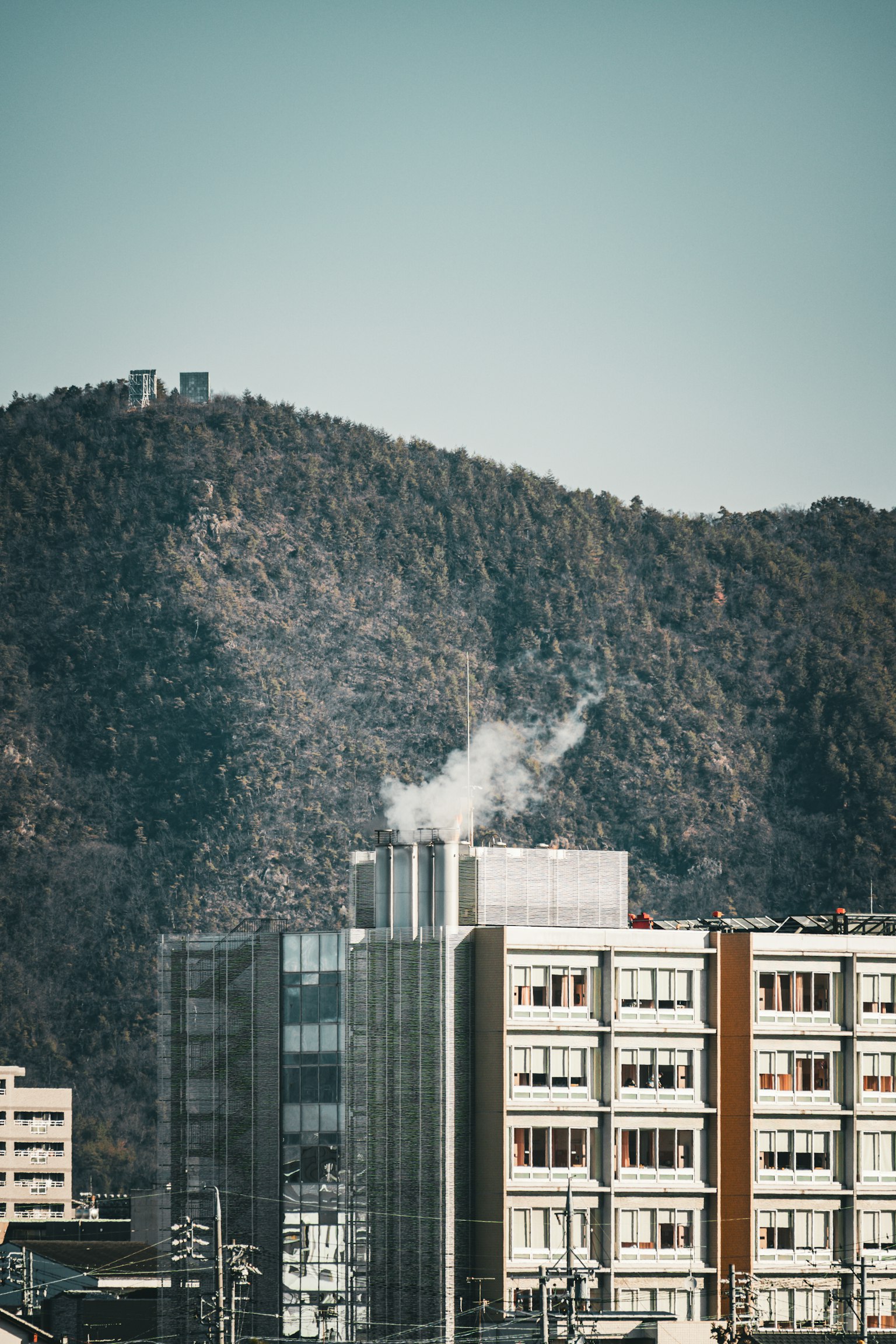 Städtische Szene mit einem Gebäude, das Rauch ausstößt, und einem Berg im Hintergrund