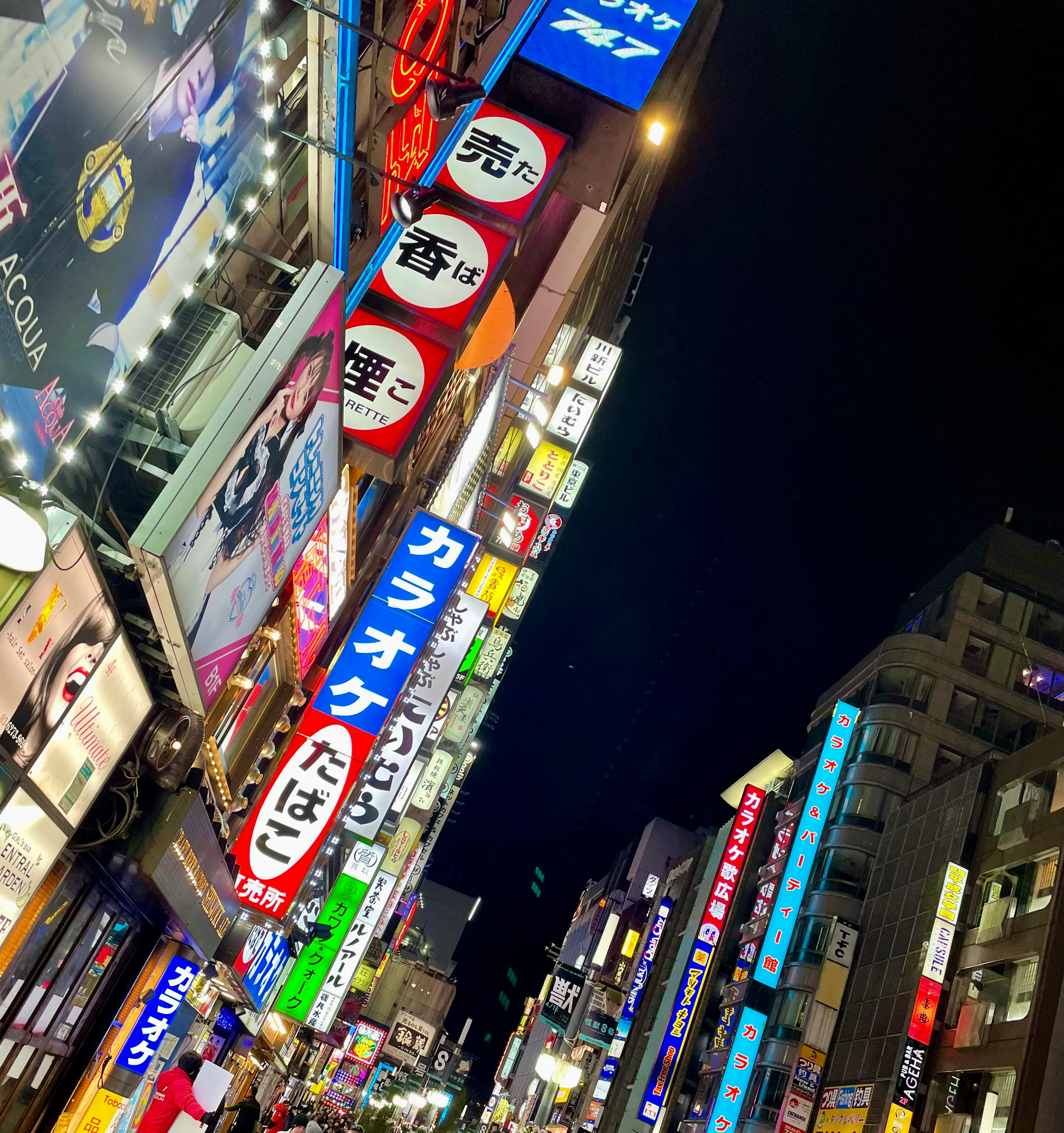 strada notturna di Shinjuku con insegne al neon
