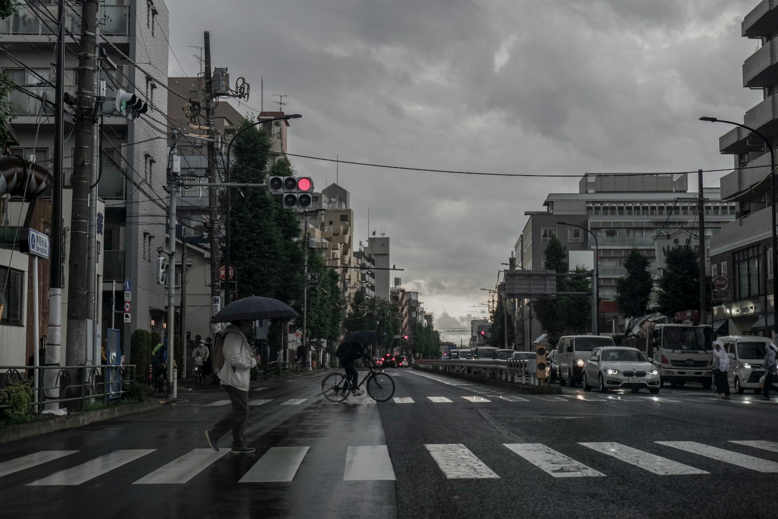 Cảnh phố đô thị với người đi bộ băng qua dưới đèn giao thông đỏ và bầu trời nhiều mây