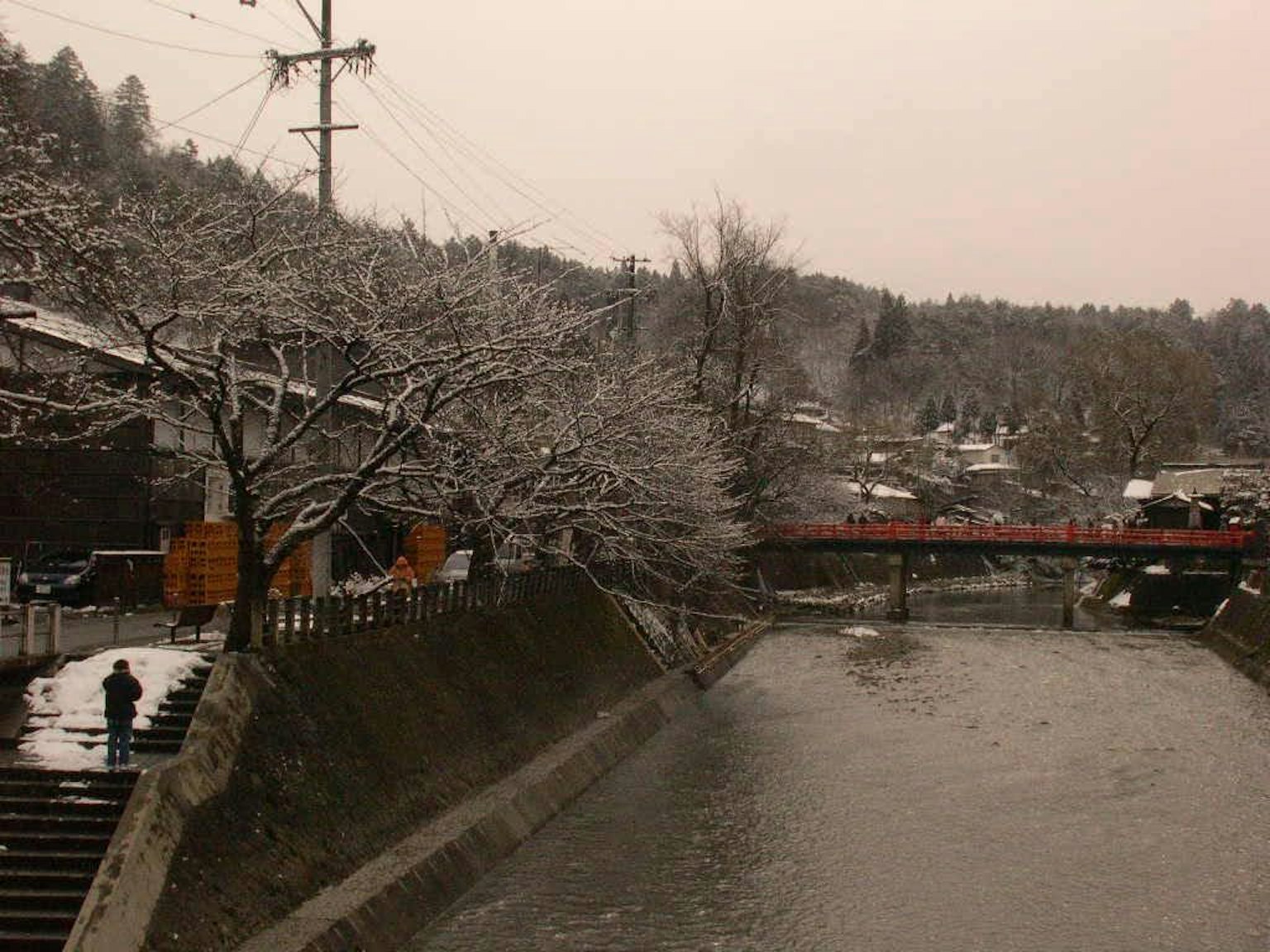Scena di fiume innevato con un ponte rosso