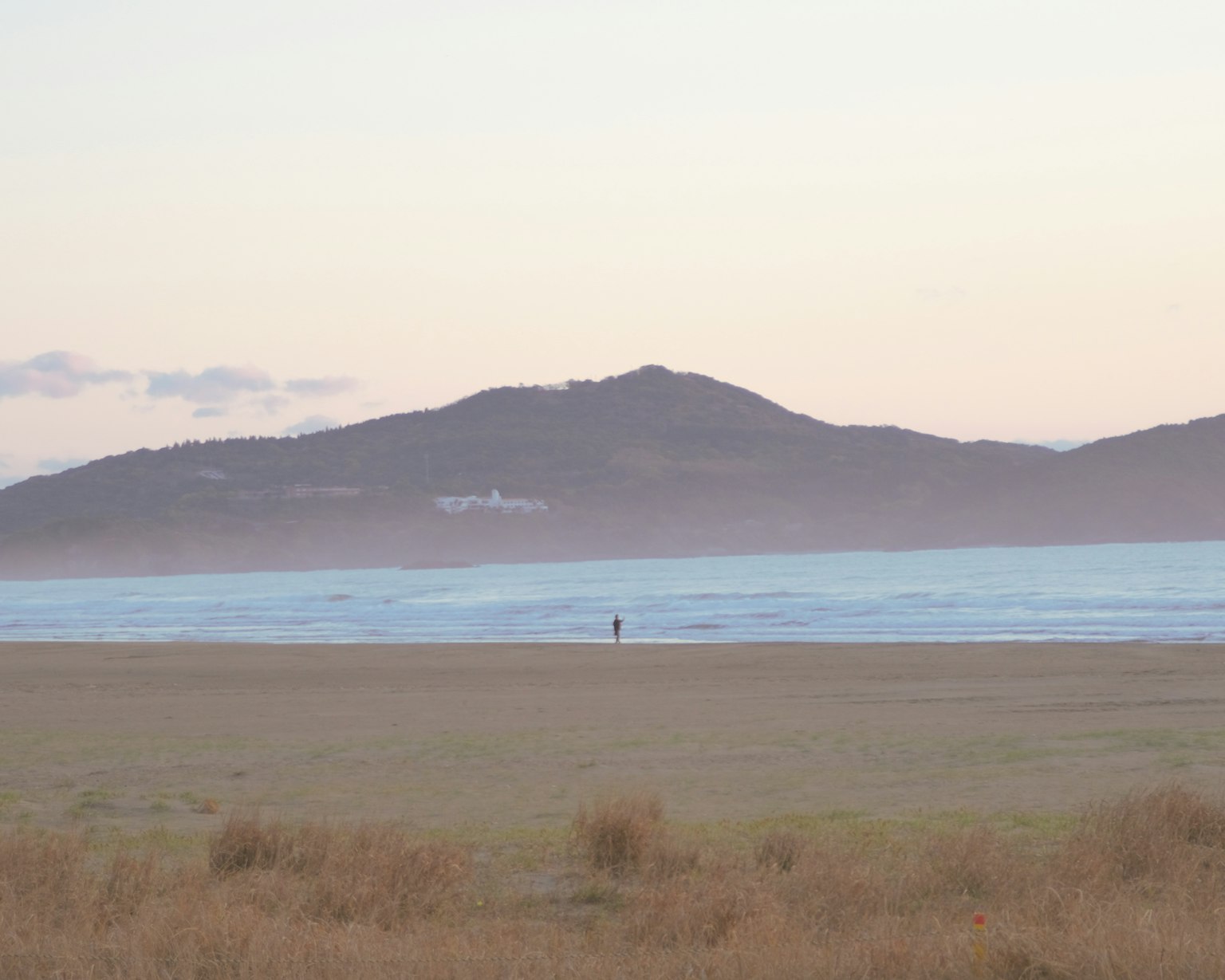 Vast beach with calm sea and distant mountains in the background