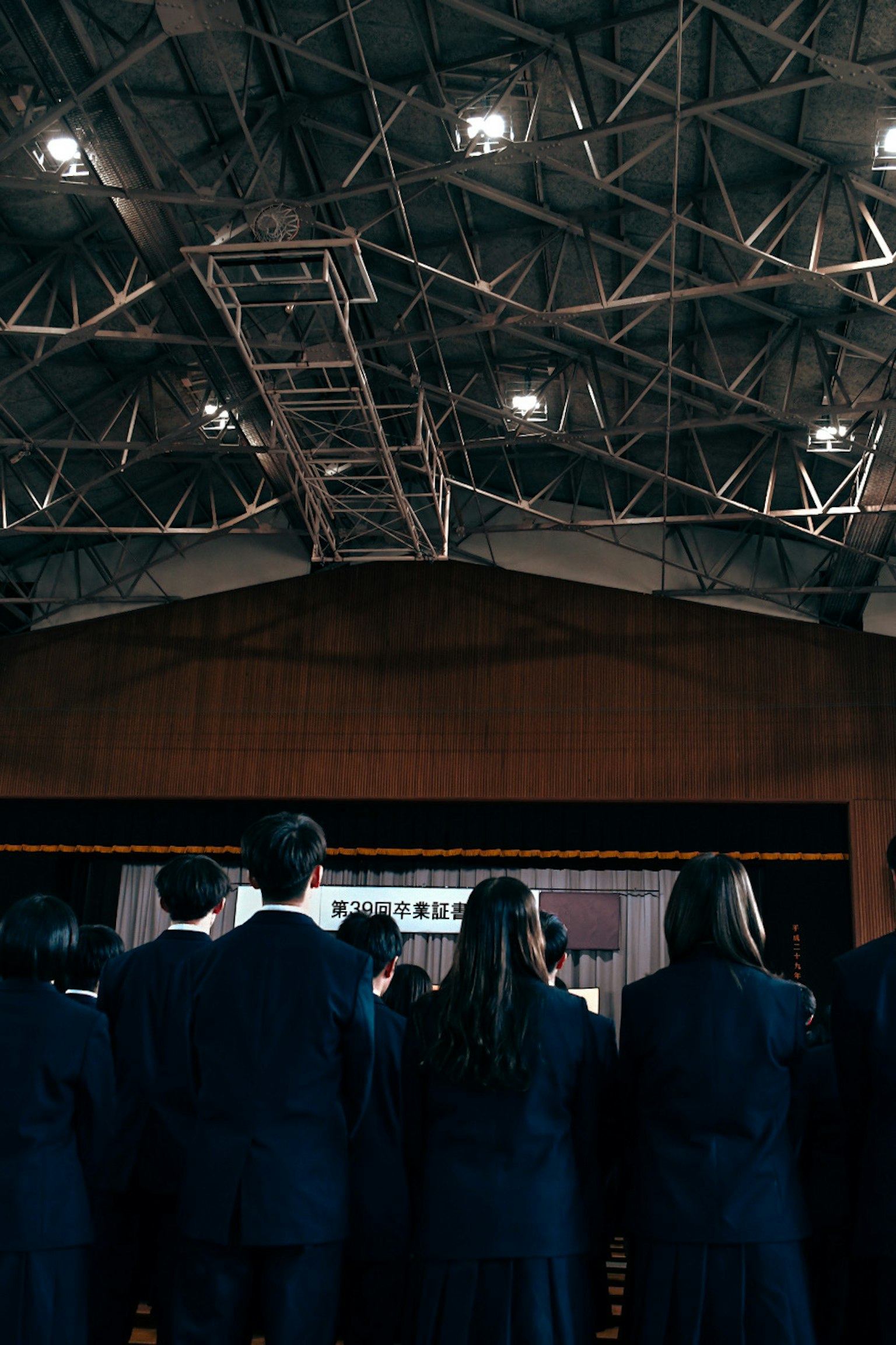 Escena de ceremonia de graduación con estudiantes en vestimenta formal mirando un escenario