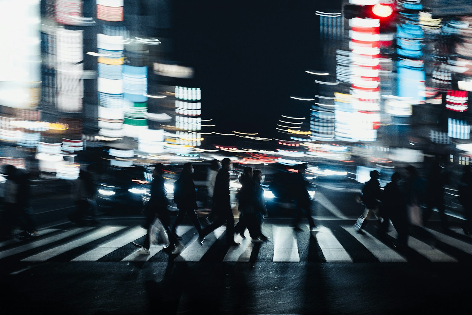 People crossing a busy street at night with bright neon lights