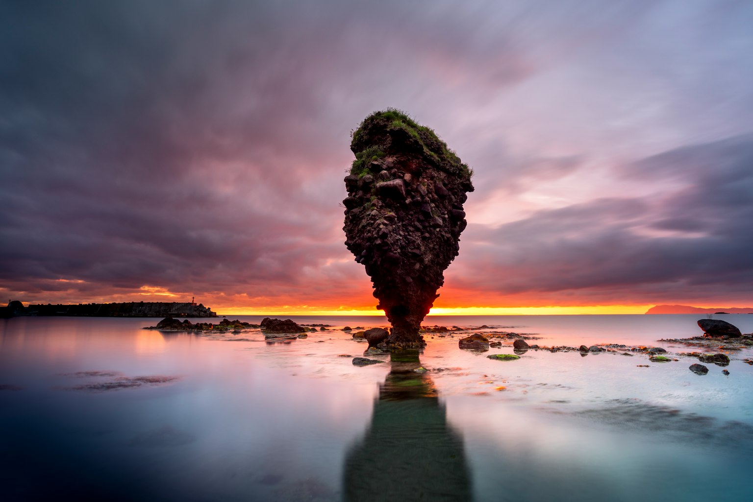 Formazione rocciosa unica in piedi al tramonto con superficie d'acqua calma