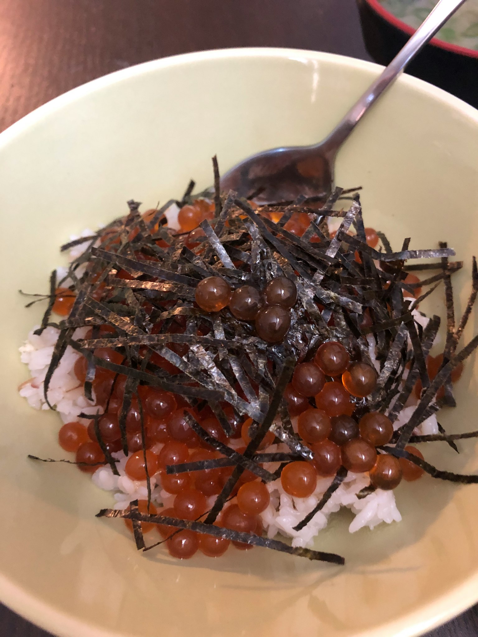 一碗米饭上放着三文鱼卵和海藻