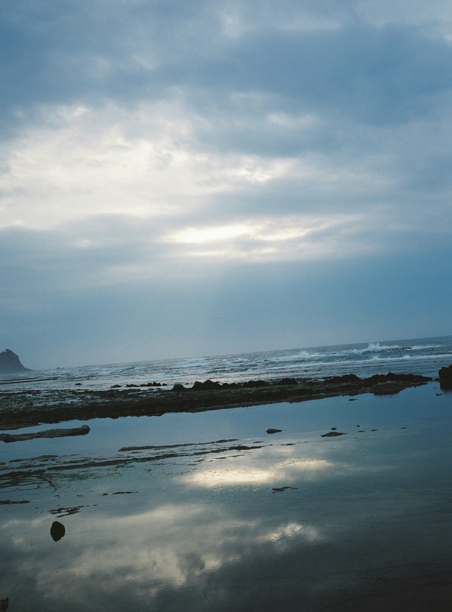Serene coastal scene with cloudy sky and water reflections