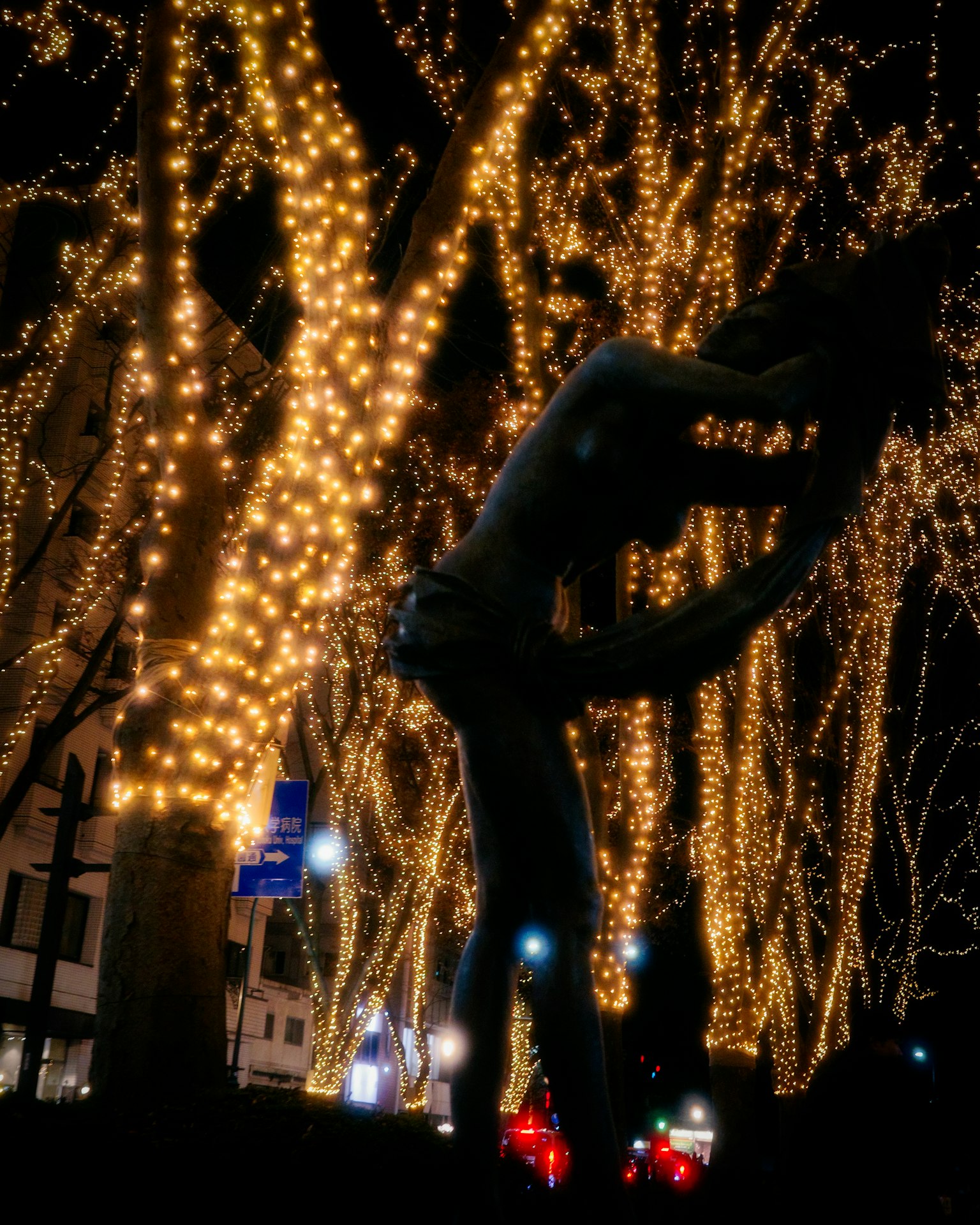 Silhouette of a couple kissing surrounded by glowing lights in a nighttime urban setting