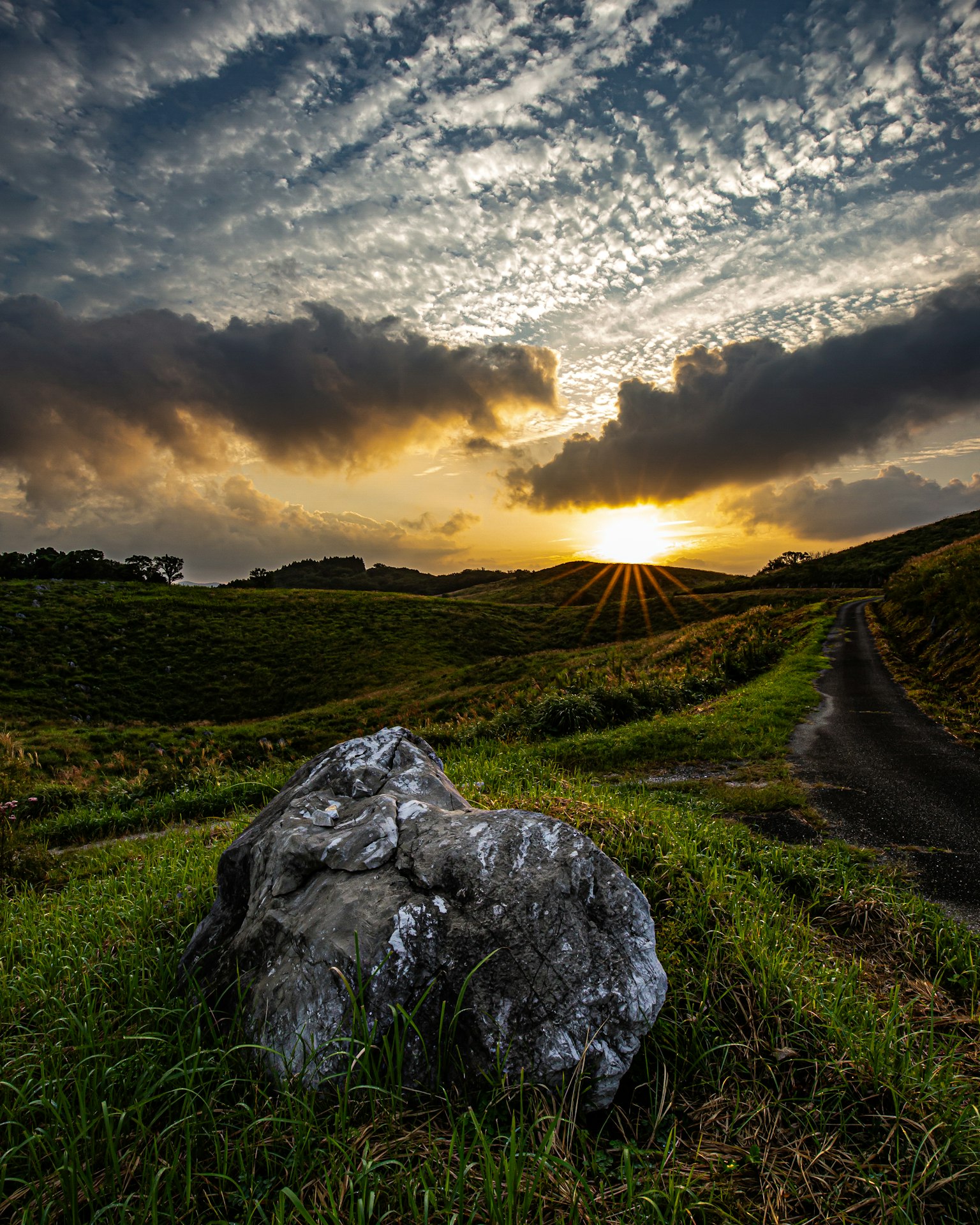 Ein großer Stein in einer malerischen Landschaft mit wunderschönem Sonnenuntergang und Wolken