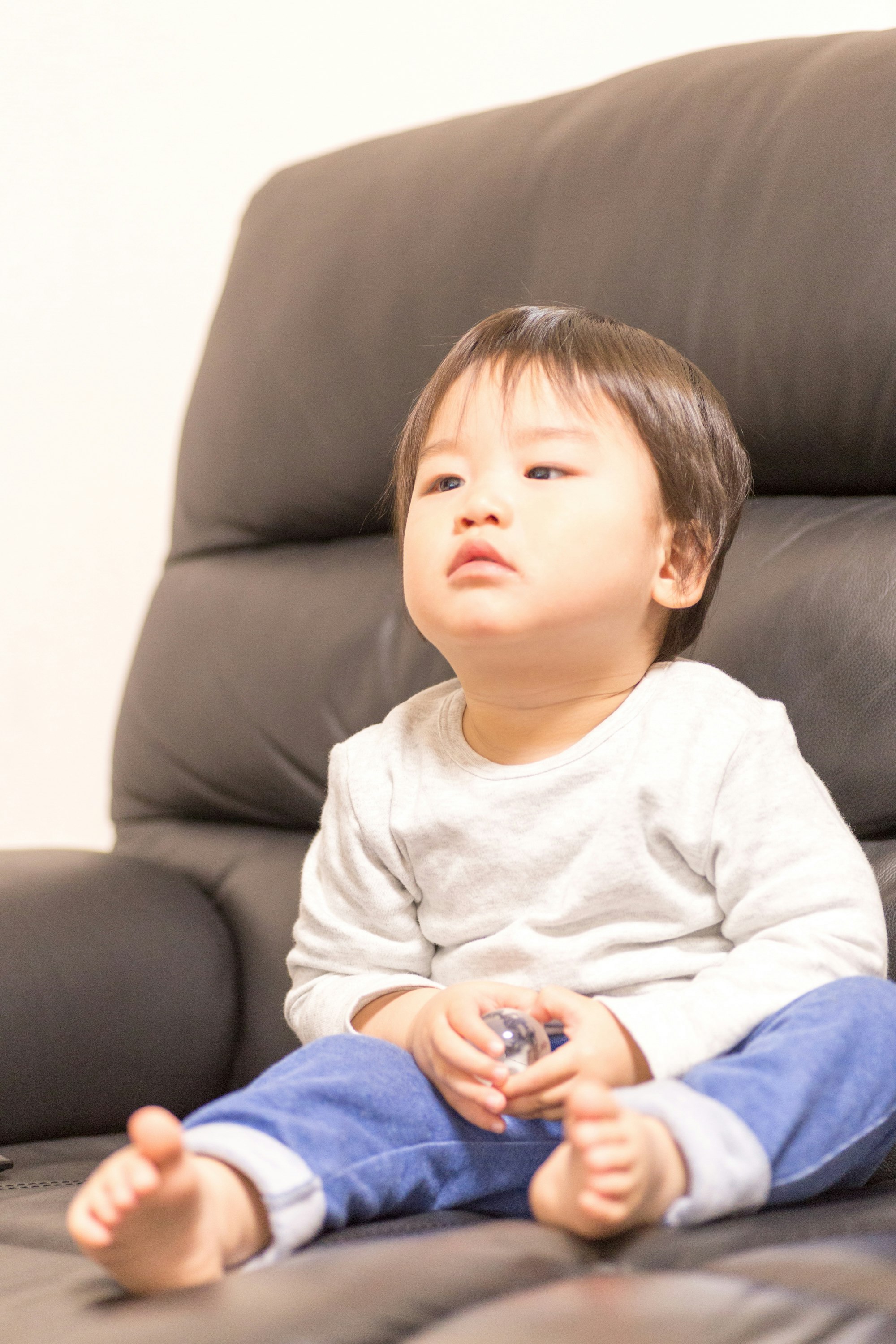 ソファに座る赤ちゃんの見上げる表情