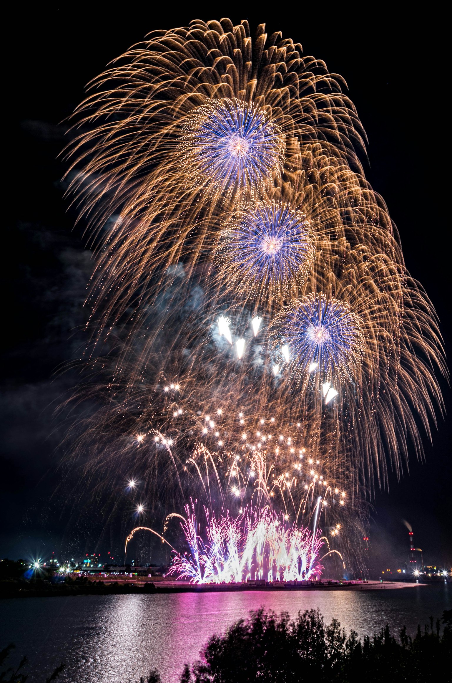 Spectacle de feux d'artifice colorés illuminant le ciel nocturne au-dessus d'un plan d'eau